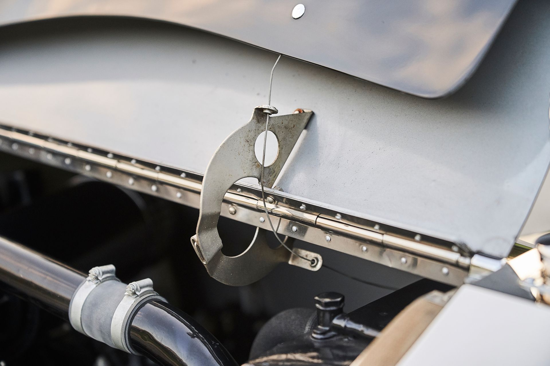 A close up of a car hood with a metal bracket attached to it