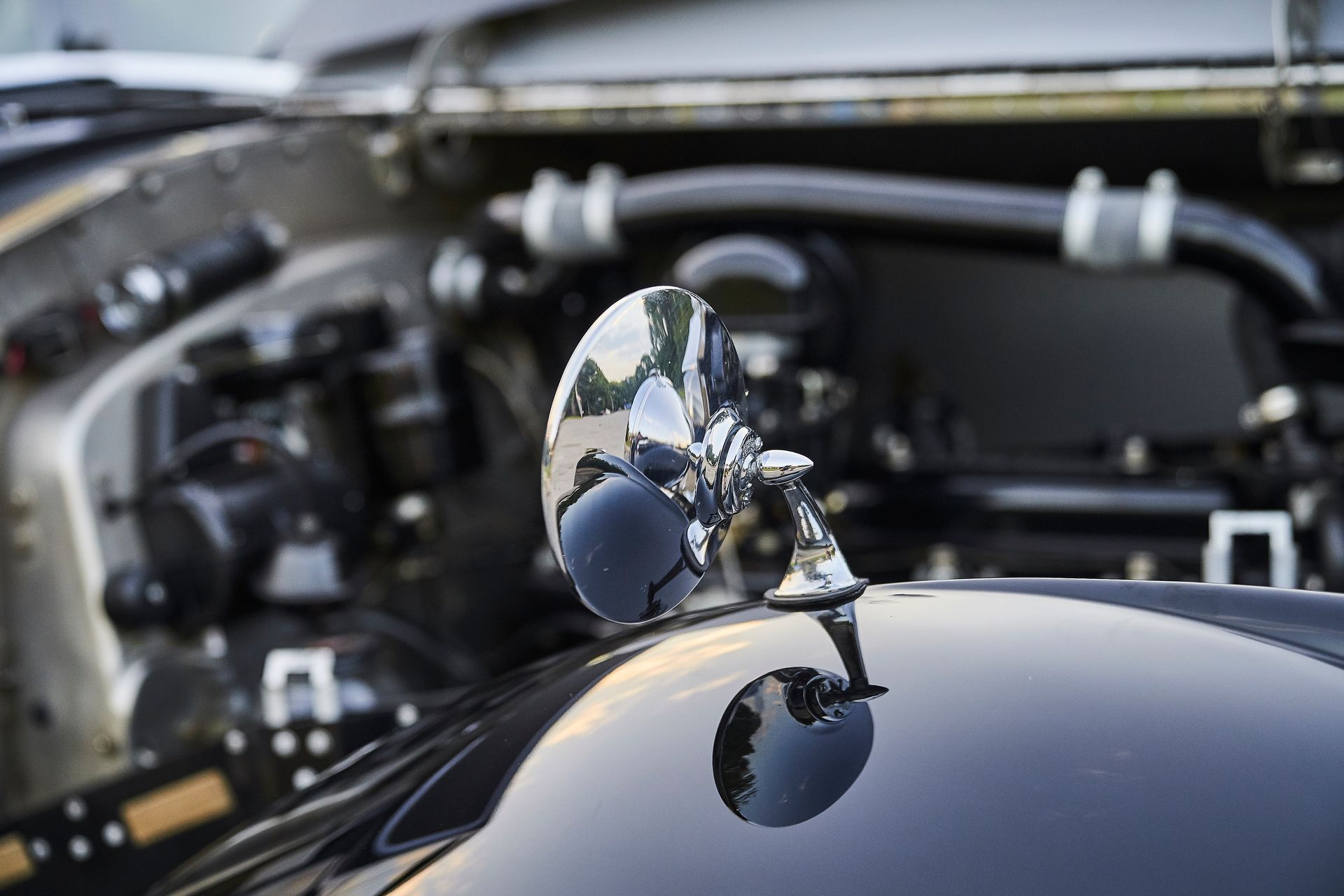 A close up of a car hood with a mirror on it.
