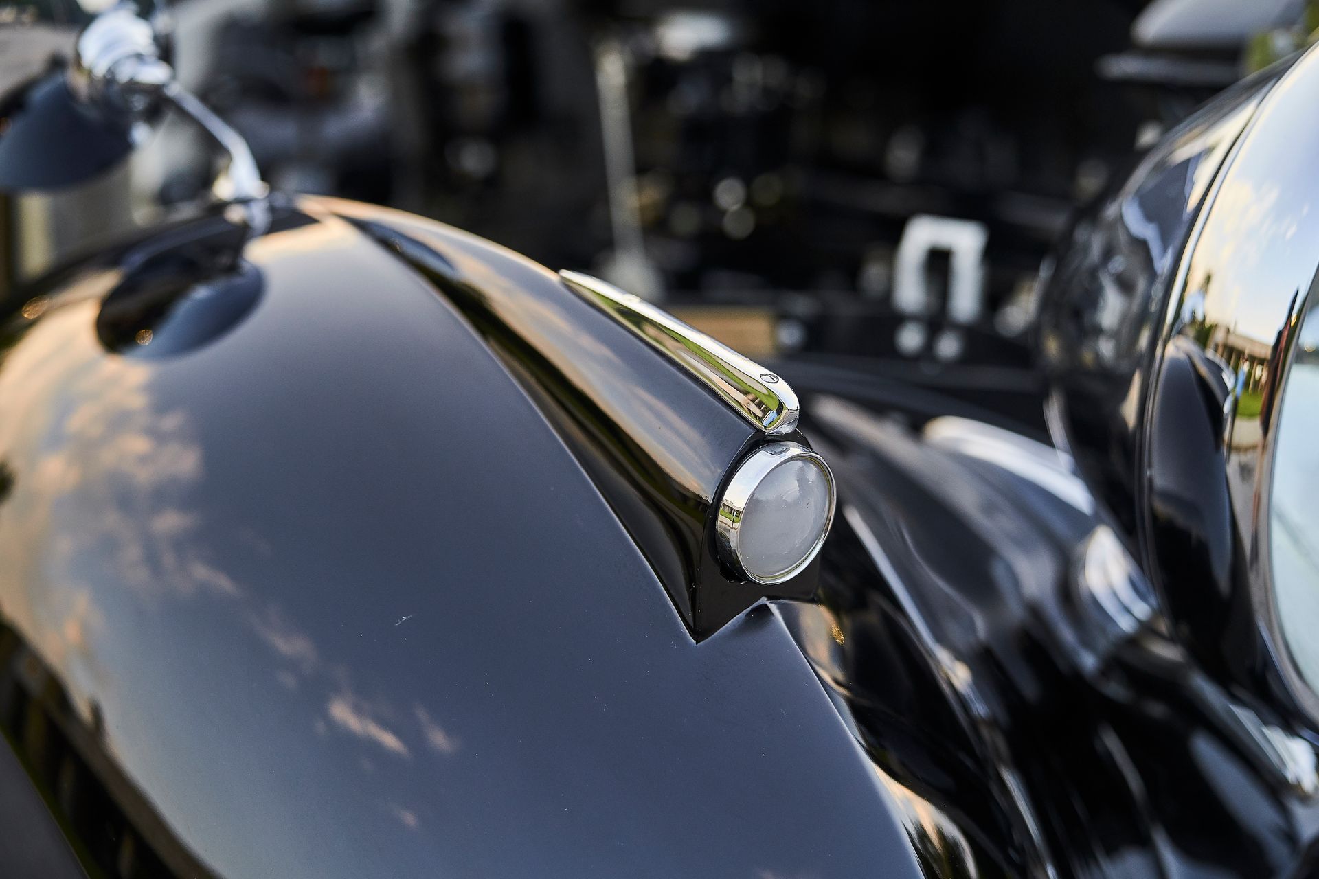 A close up of a black car with a chrome hood ornament.