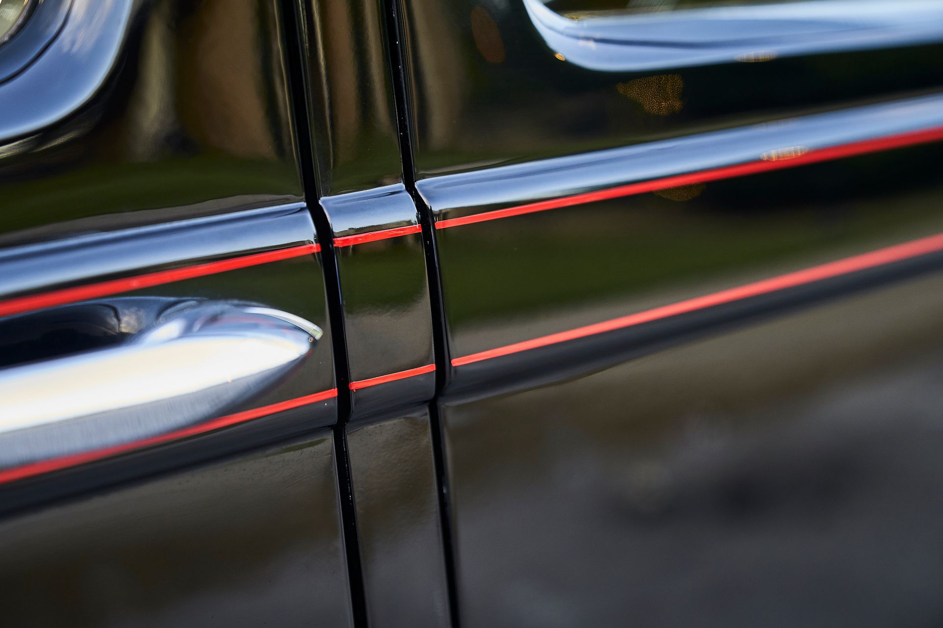 A close up of a black car with red stripes on the door handles.