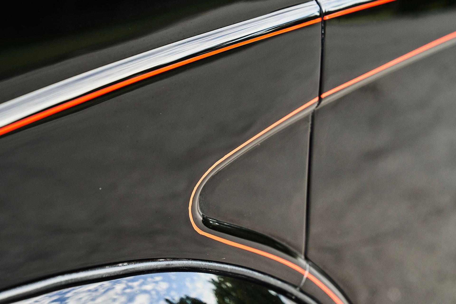 A close up of a black car with orange stripes on the side