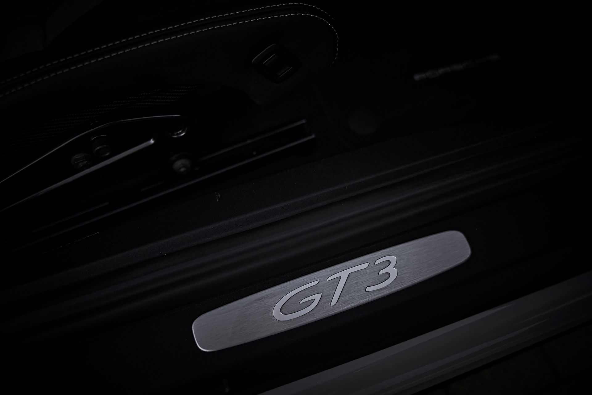 The door sill of a porsche 911 gt3 is lit up in the dark.