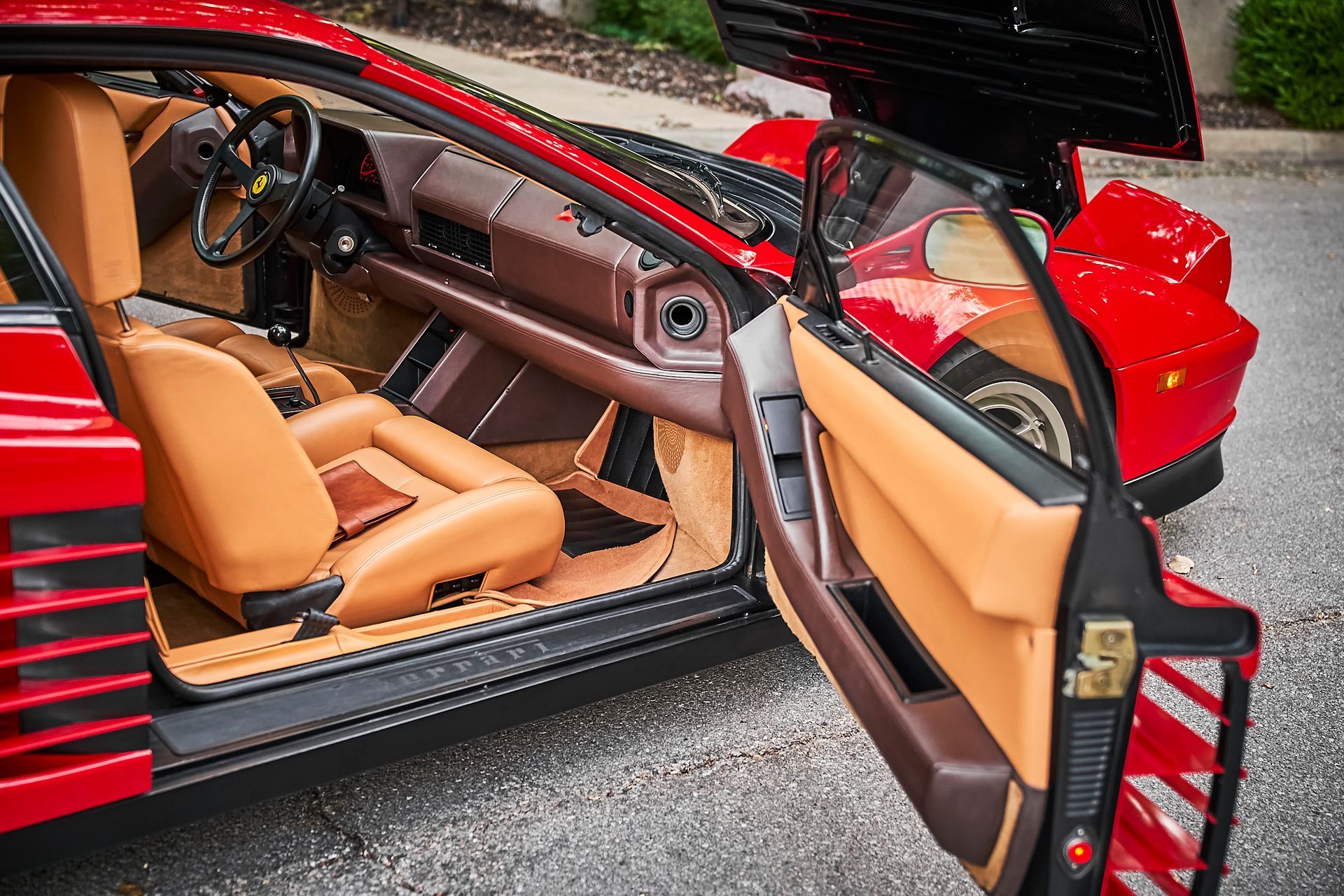 A red sports car with the door open and the hood up