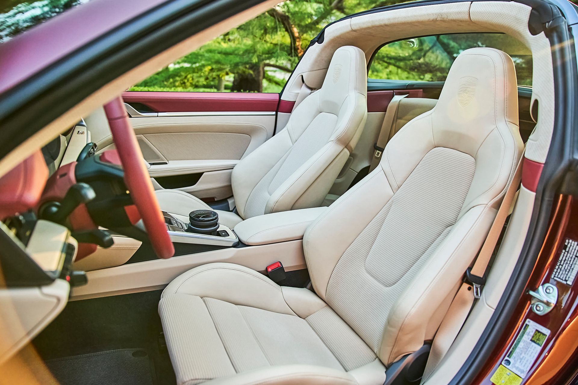 The inside of a car with white seats and a red steering wheel.