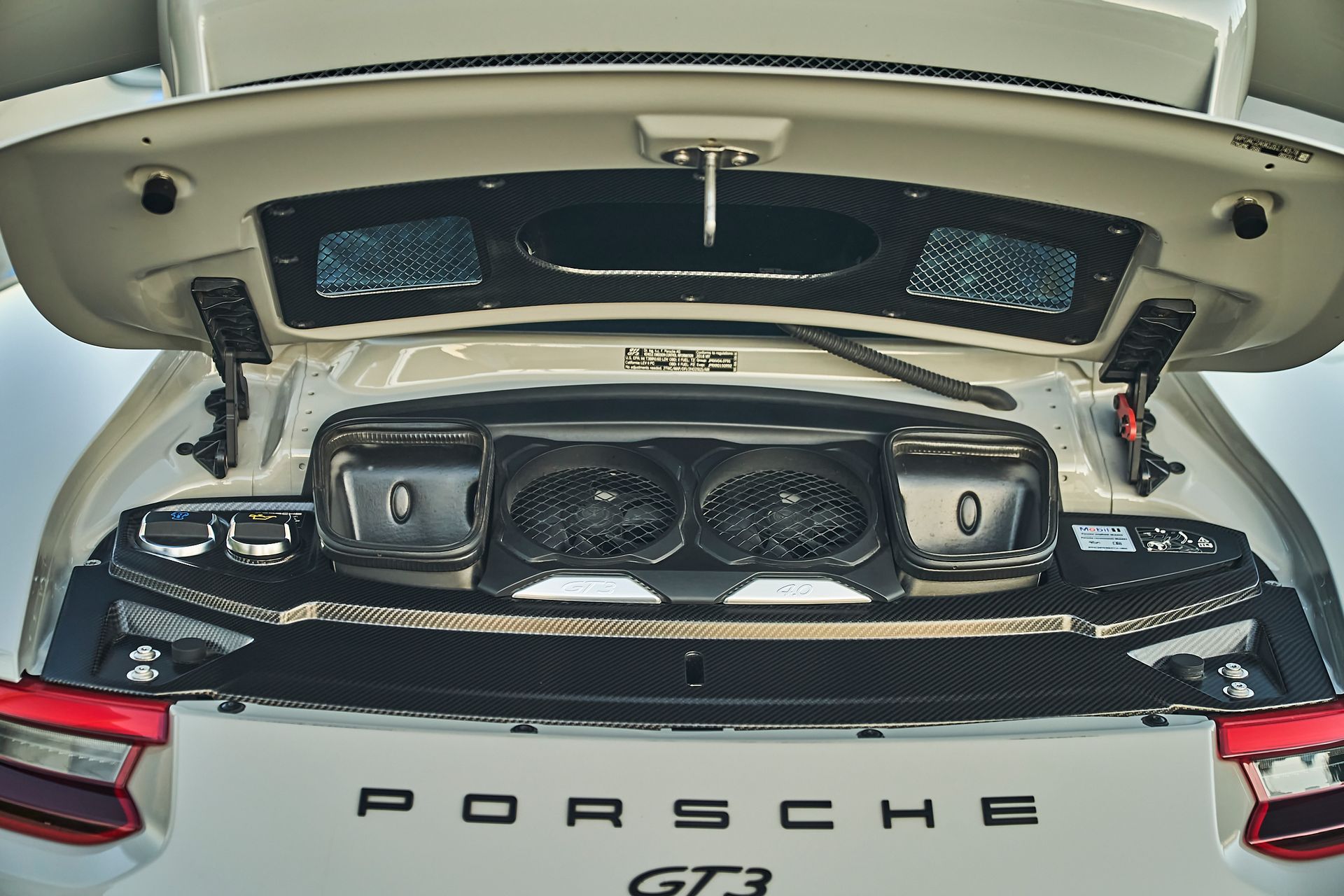 The trunk of a porsche gt3 with the hood open.