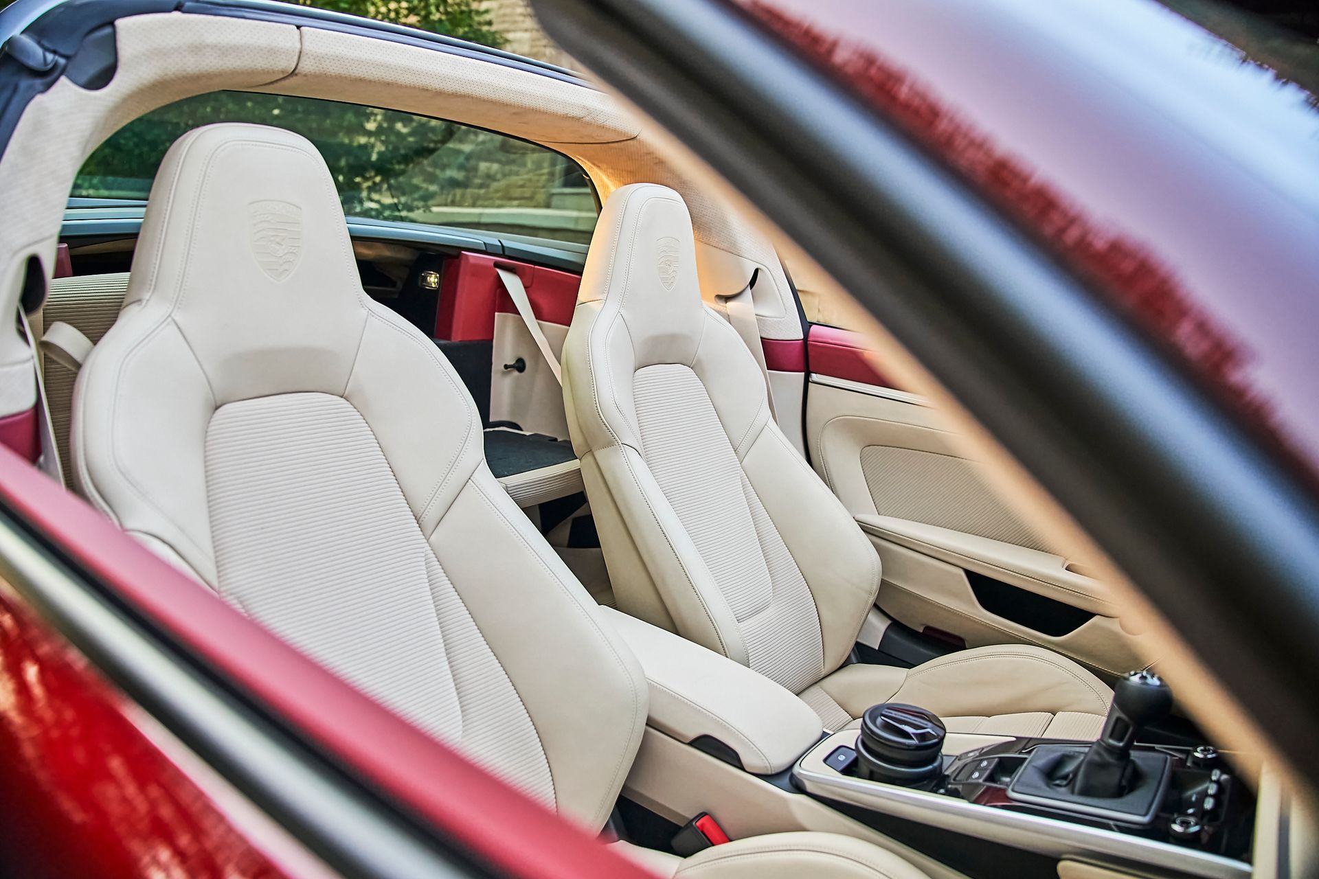 The interior of a red sports car with white leather seats.