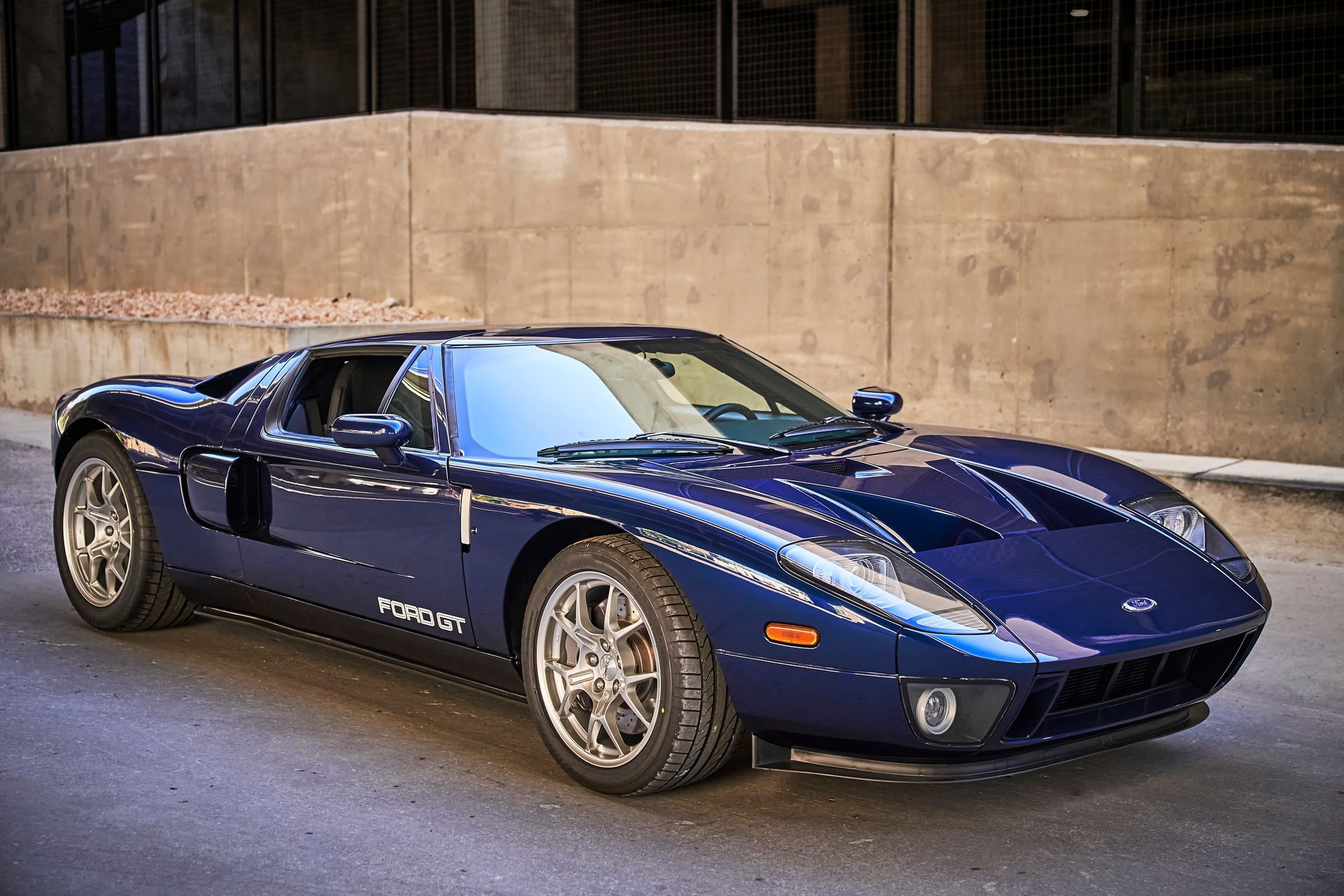 2006 Ford GT -A blue sports car is parked on the side of the road in front of a building.