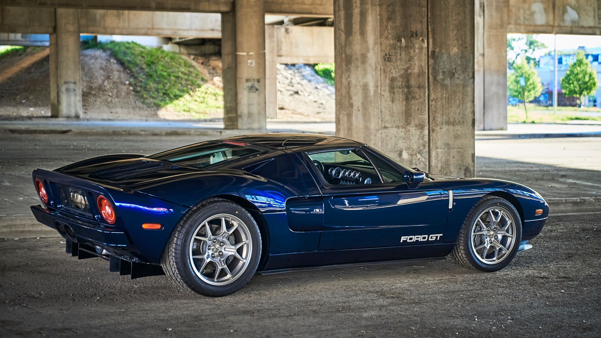 2006 Ford GT -A blue sports car is parked under a bridge in a parking lot.