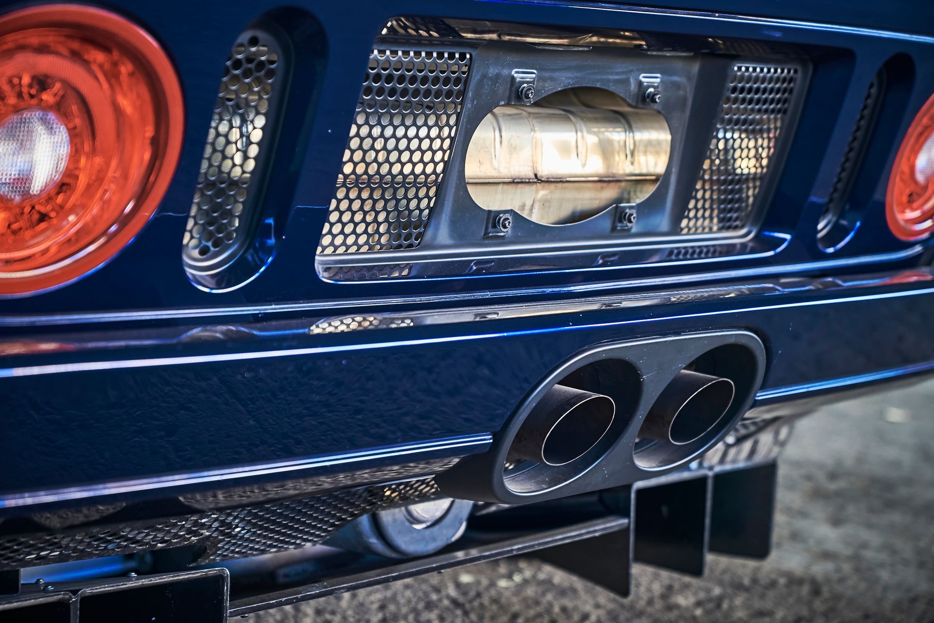 A close up of a blue car with red lights and exhaust pipes.