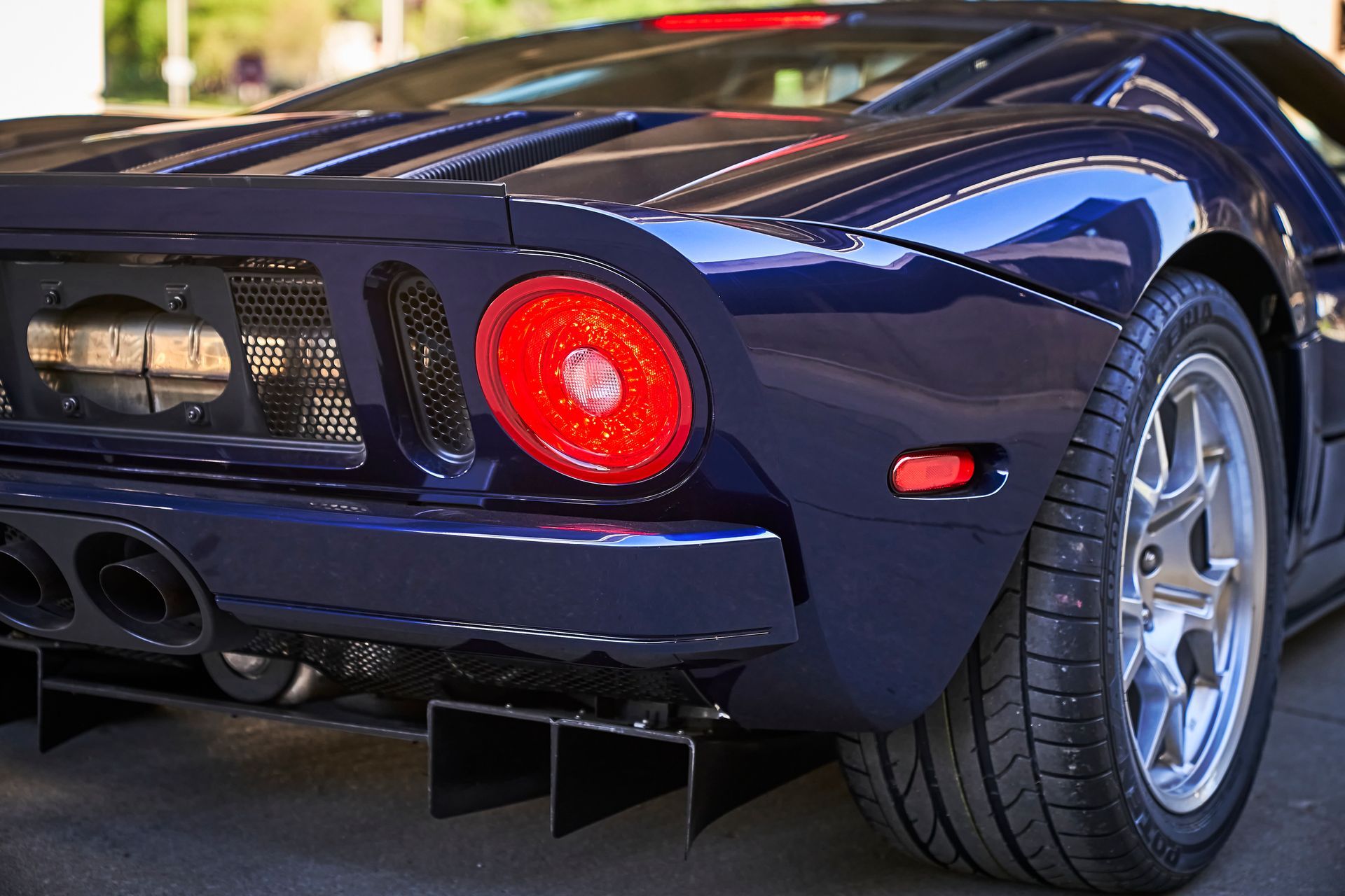 2006 Ford GT -A blue sports car with a red tail light is parked on the street.
