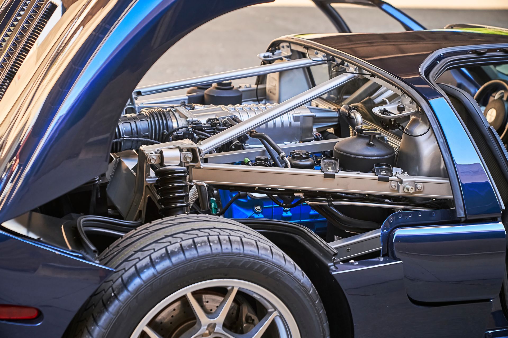 The engine of a blue sports car with the hood open