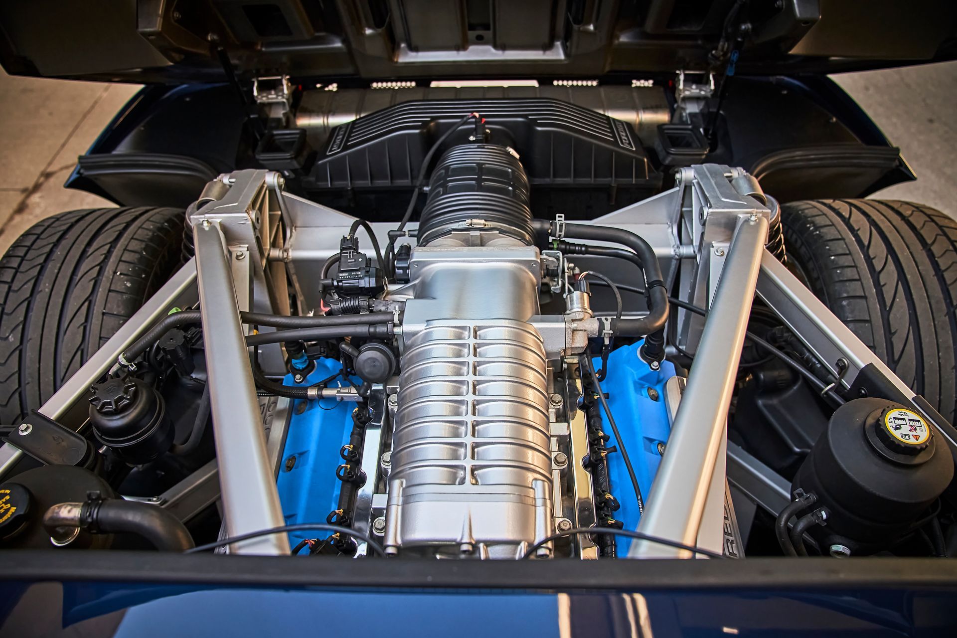 A close up of the engine of a car with the hood up.