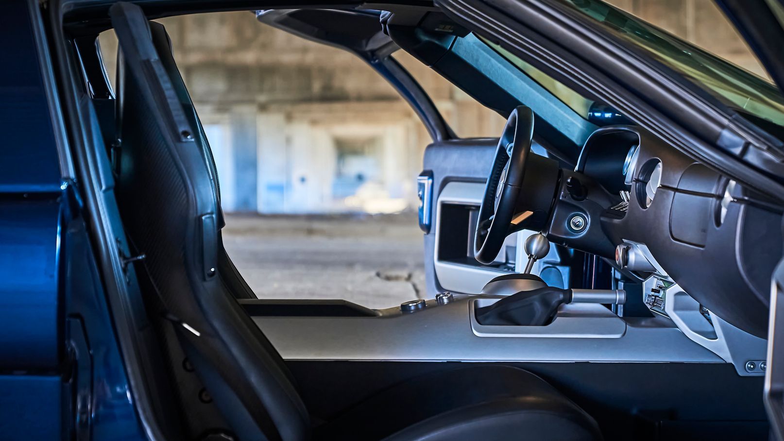 The inside of a blue car with the door open and the steering wheel visible.