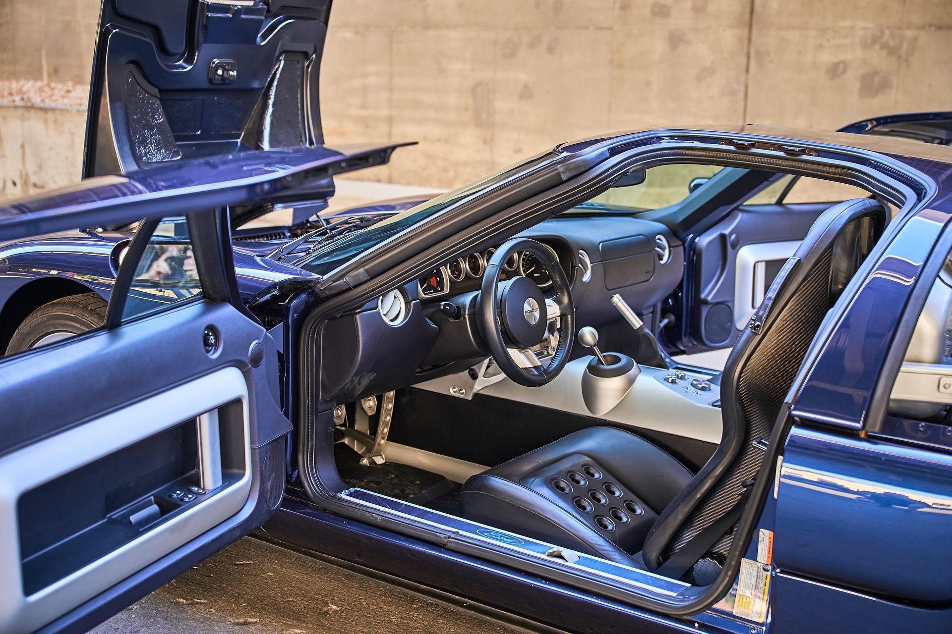 The interior of a blue sports car with its doors open.
