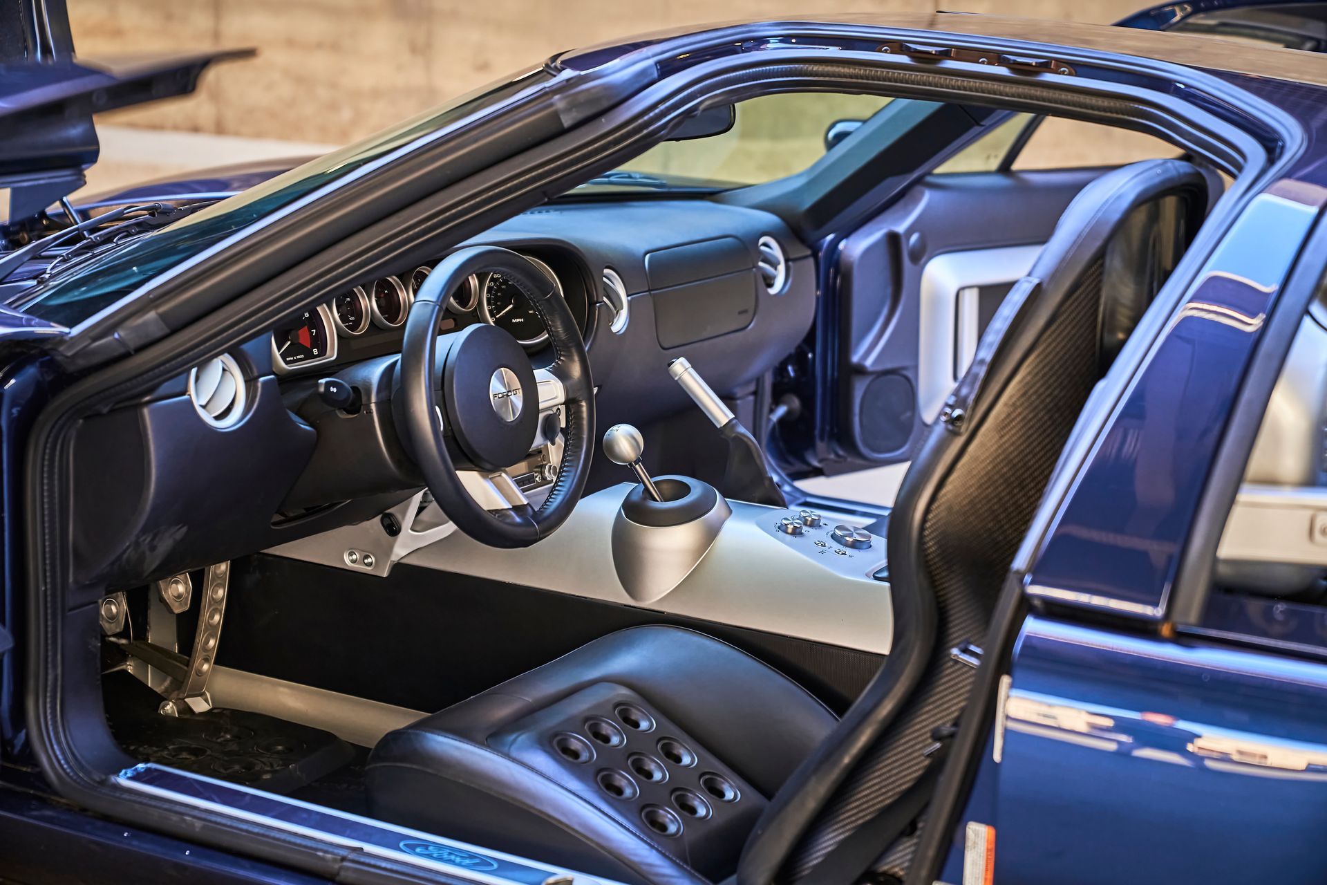The interior of a blue sports car with the door open.