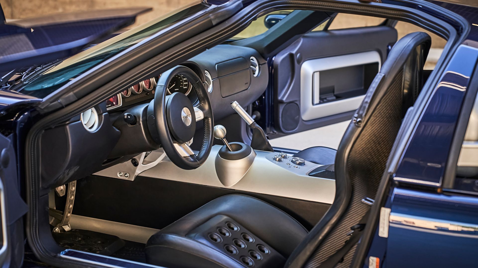 The interior of a blue sports car with the door open.
