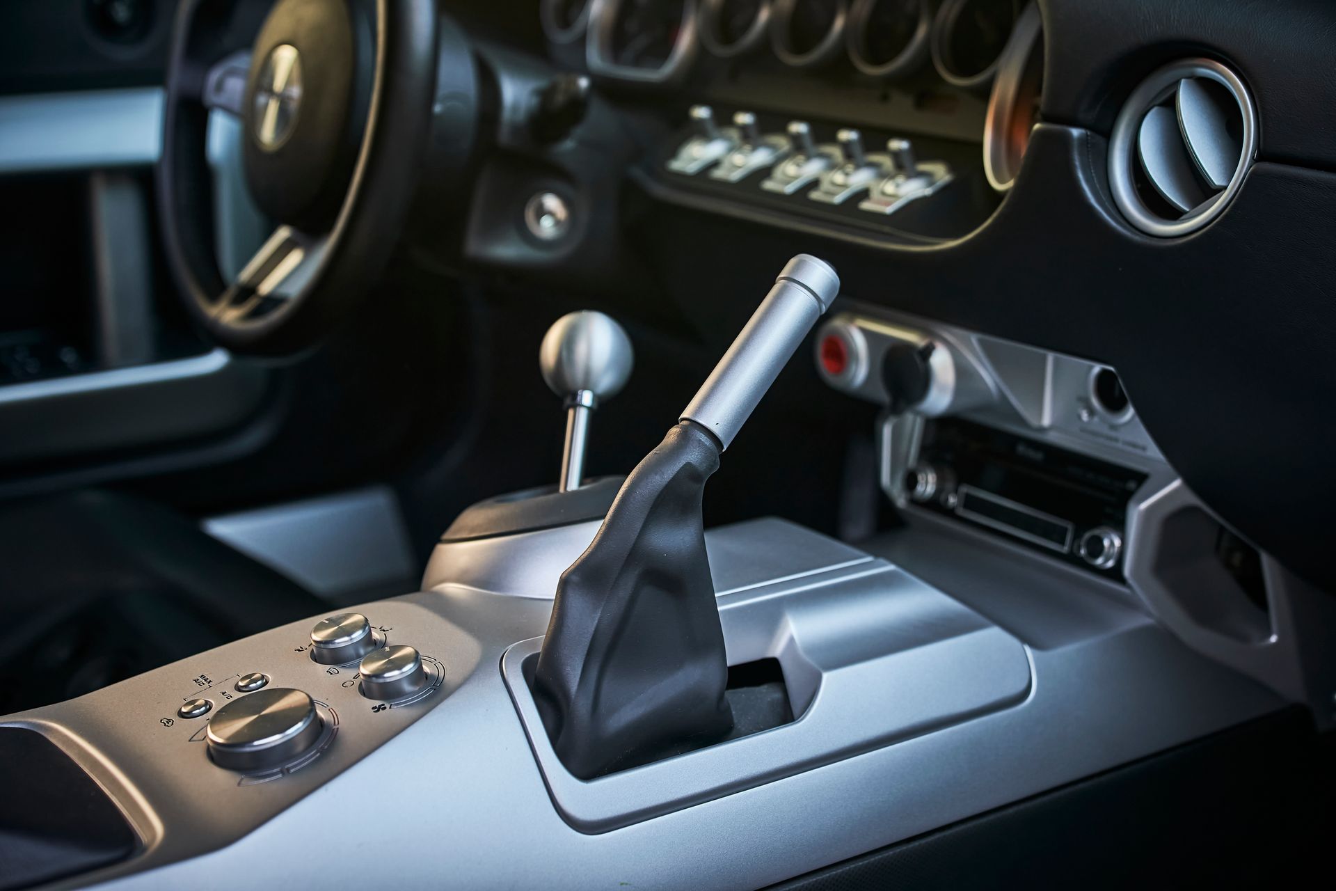 A close up of a car 's shifter and steering wheel