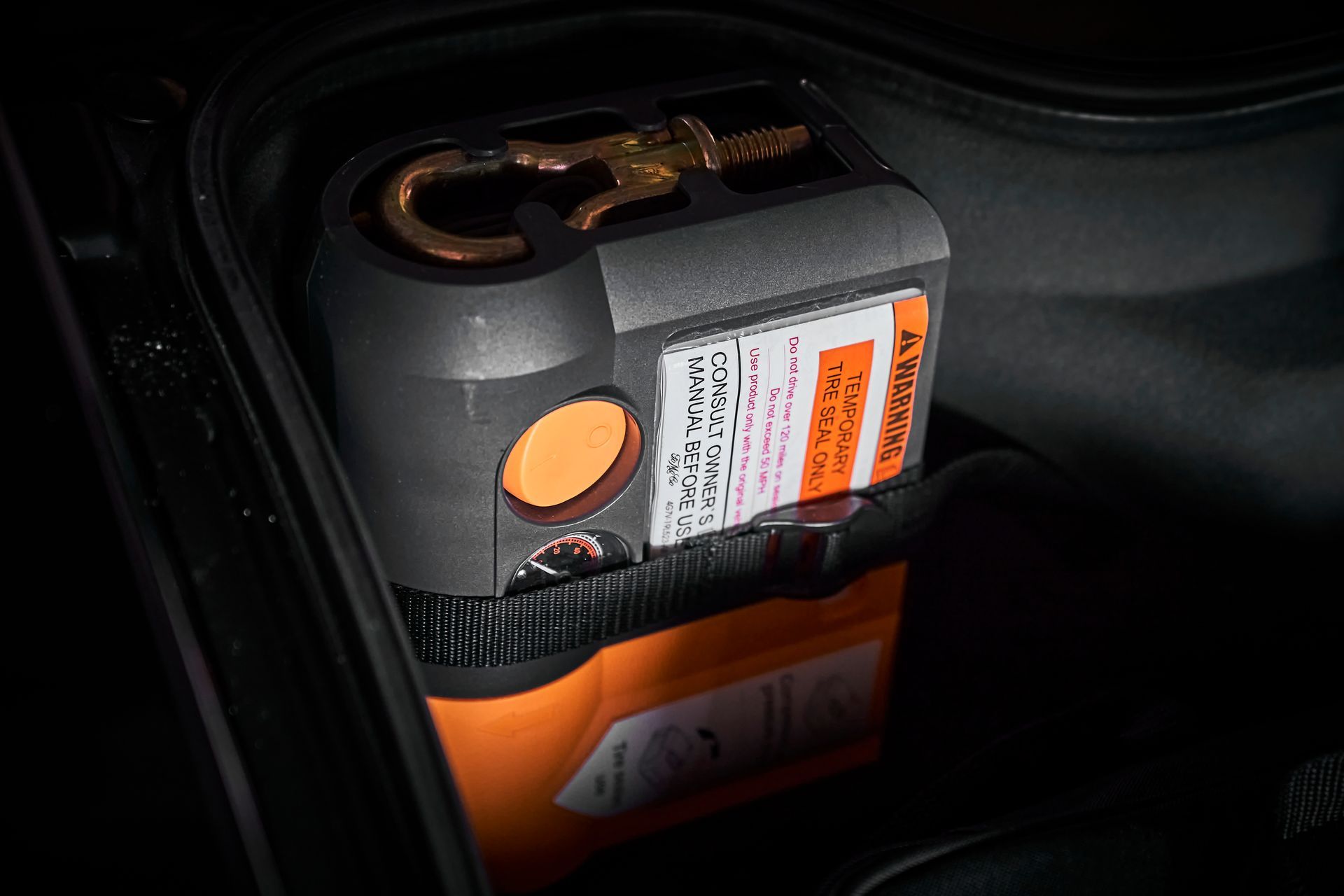 A tire pump is sitting in the trunk of a car.