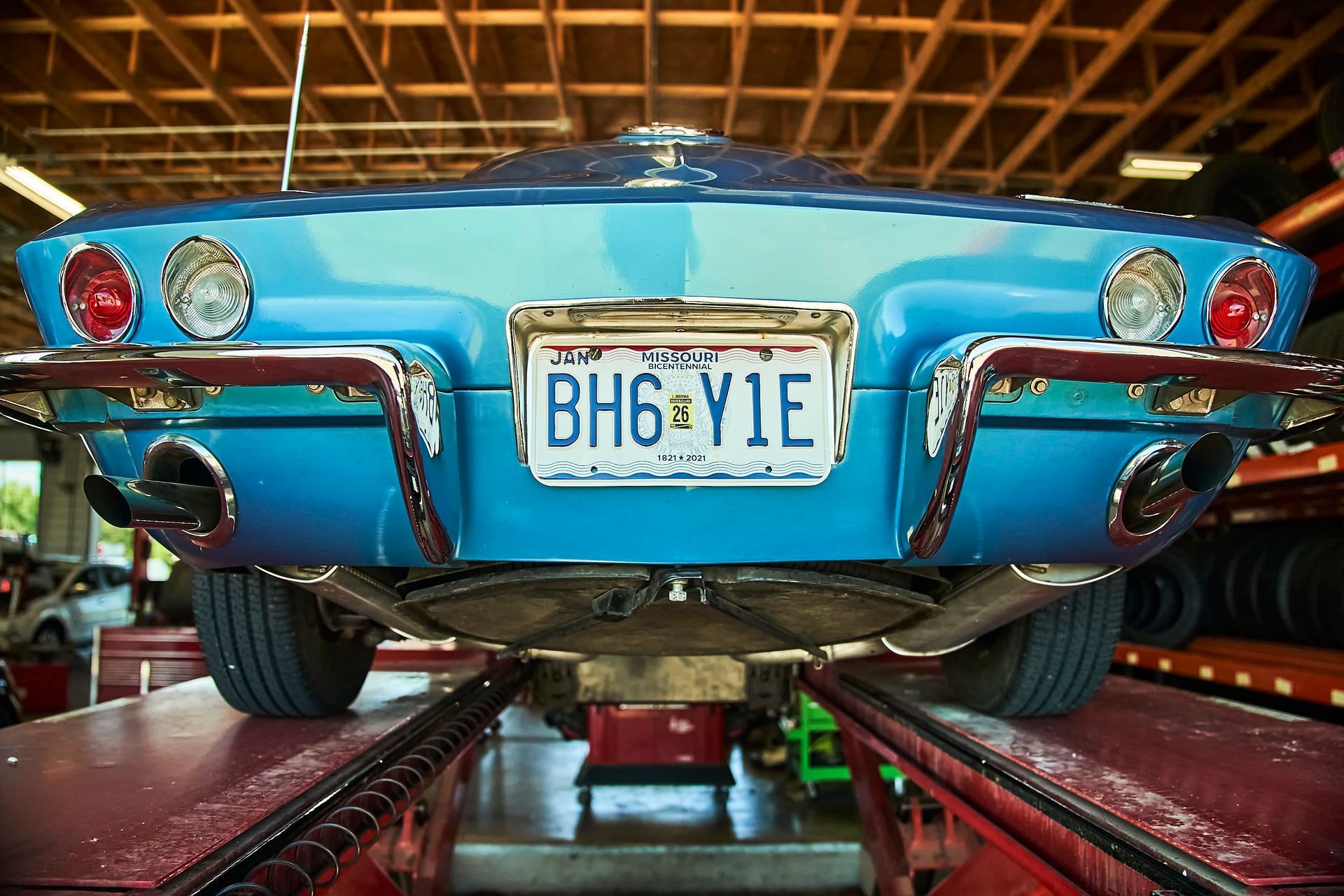 Blue classic car on a lift, license plate reads 