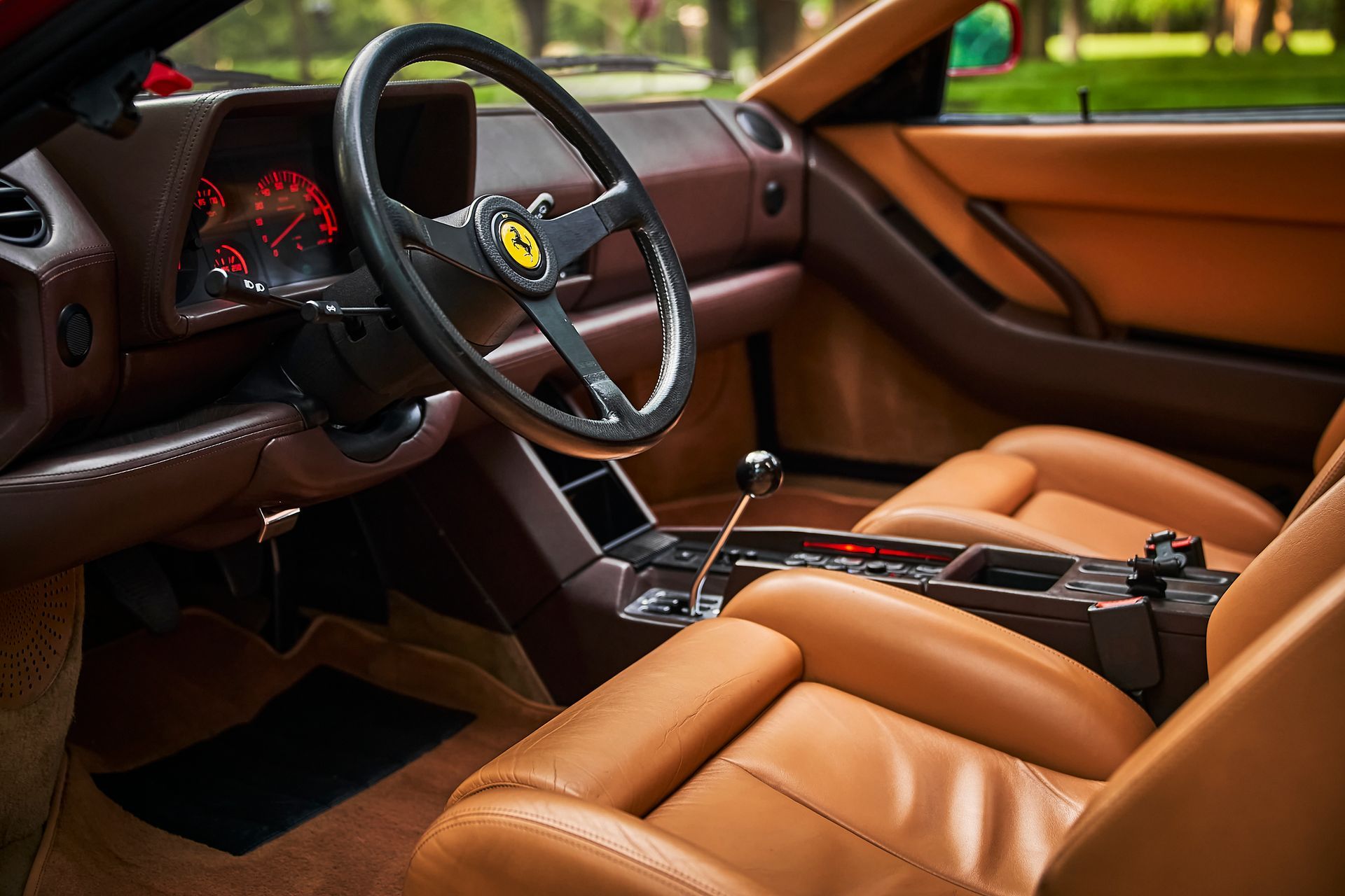 The interior of a ferrari with brown leather seats and a steering wheel