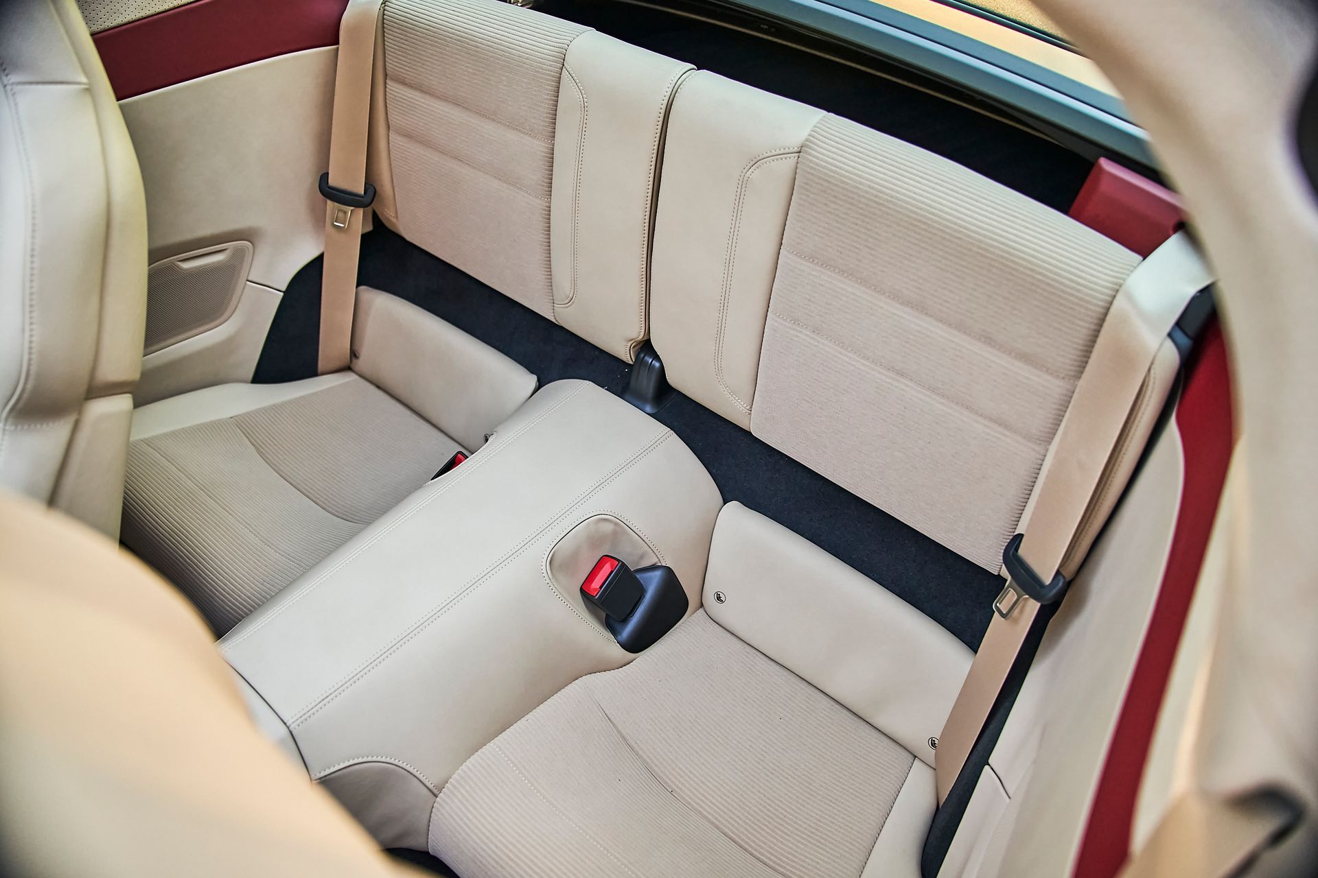 The back seat of a car with a red seat belt