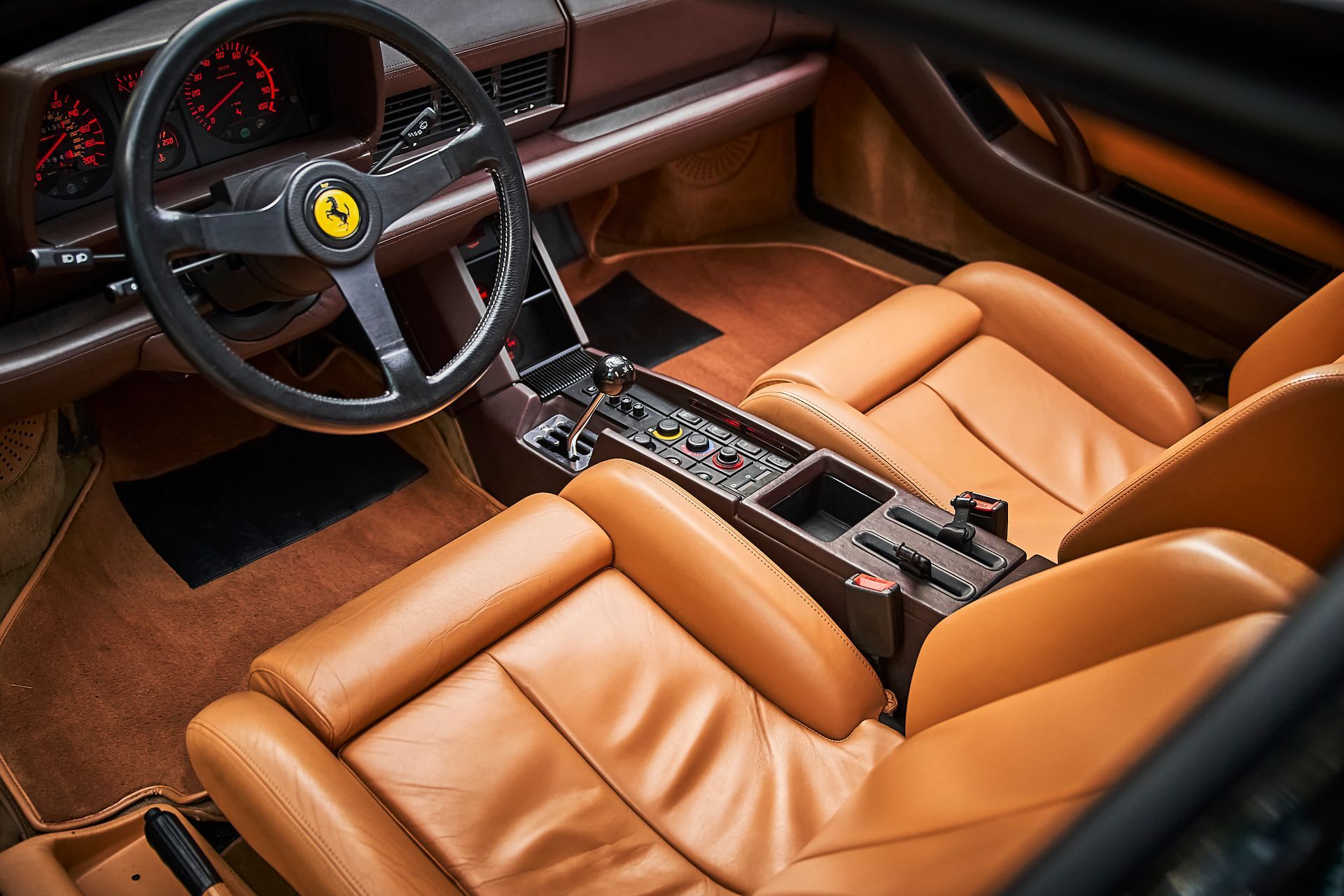 The interior of a ferrari with brown leather seats and a steering wheel.