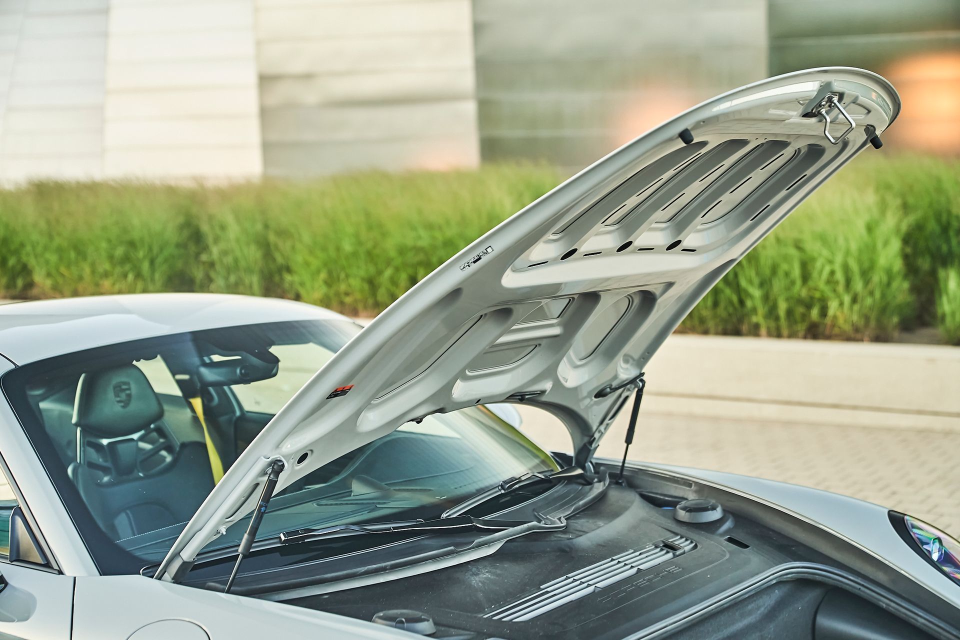 The hood of a car is open and the windshield is visible.