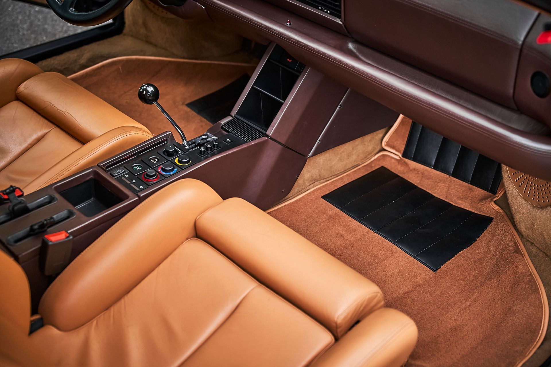 The interior of a car with brown leather seats and a black mat.