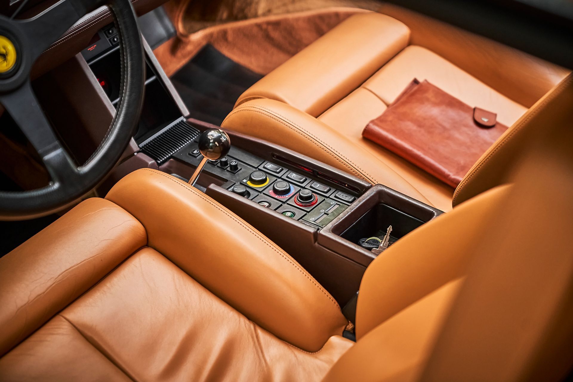 The interior of a ferrari with brown leather seats and a steering wheel.