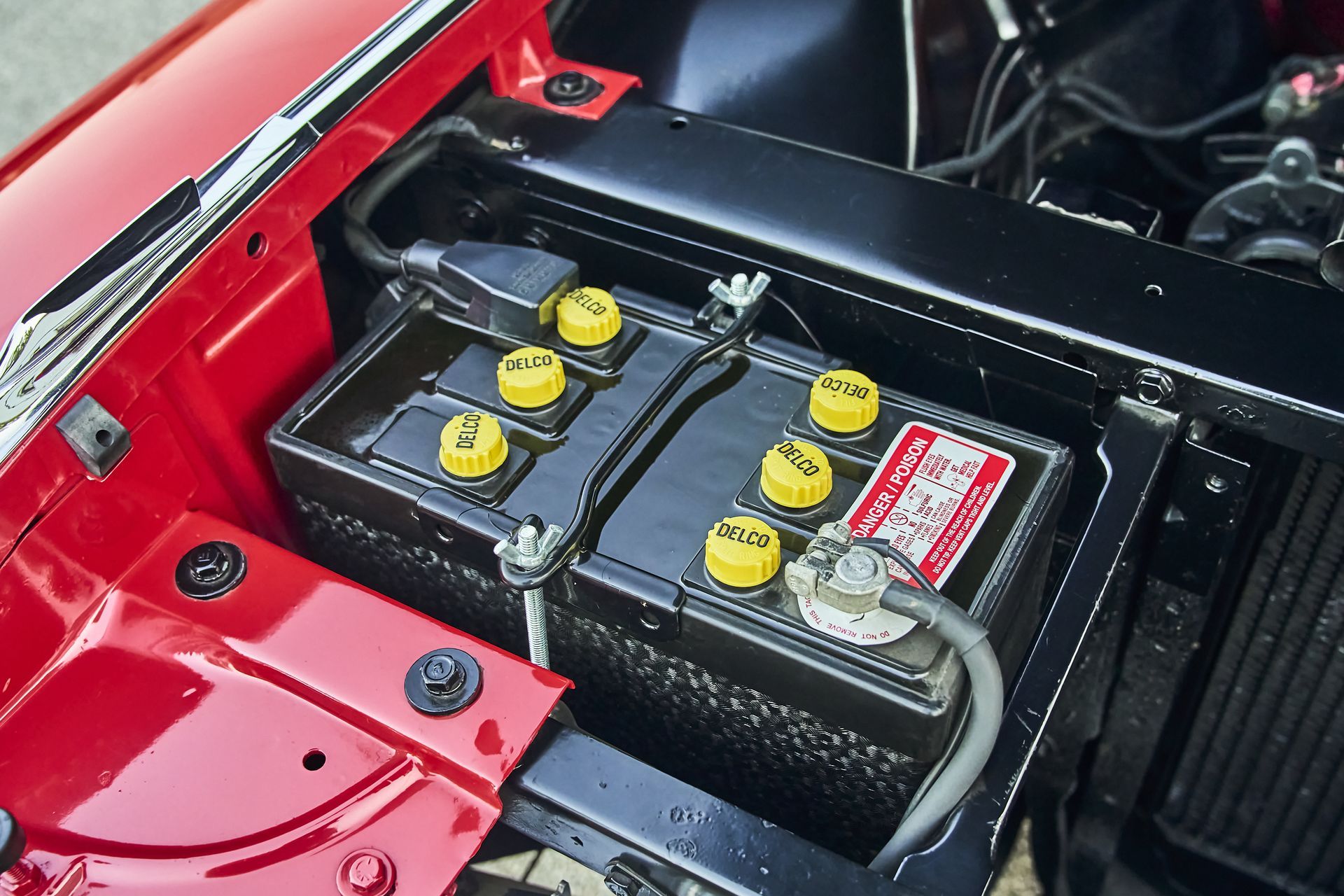 A red car with a battery in the trunk