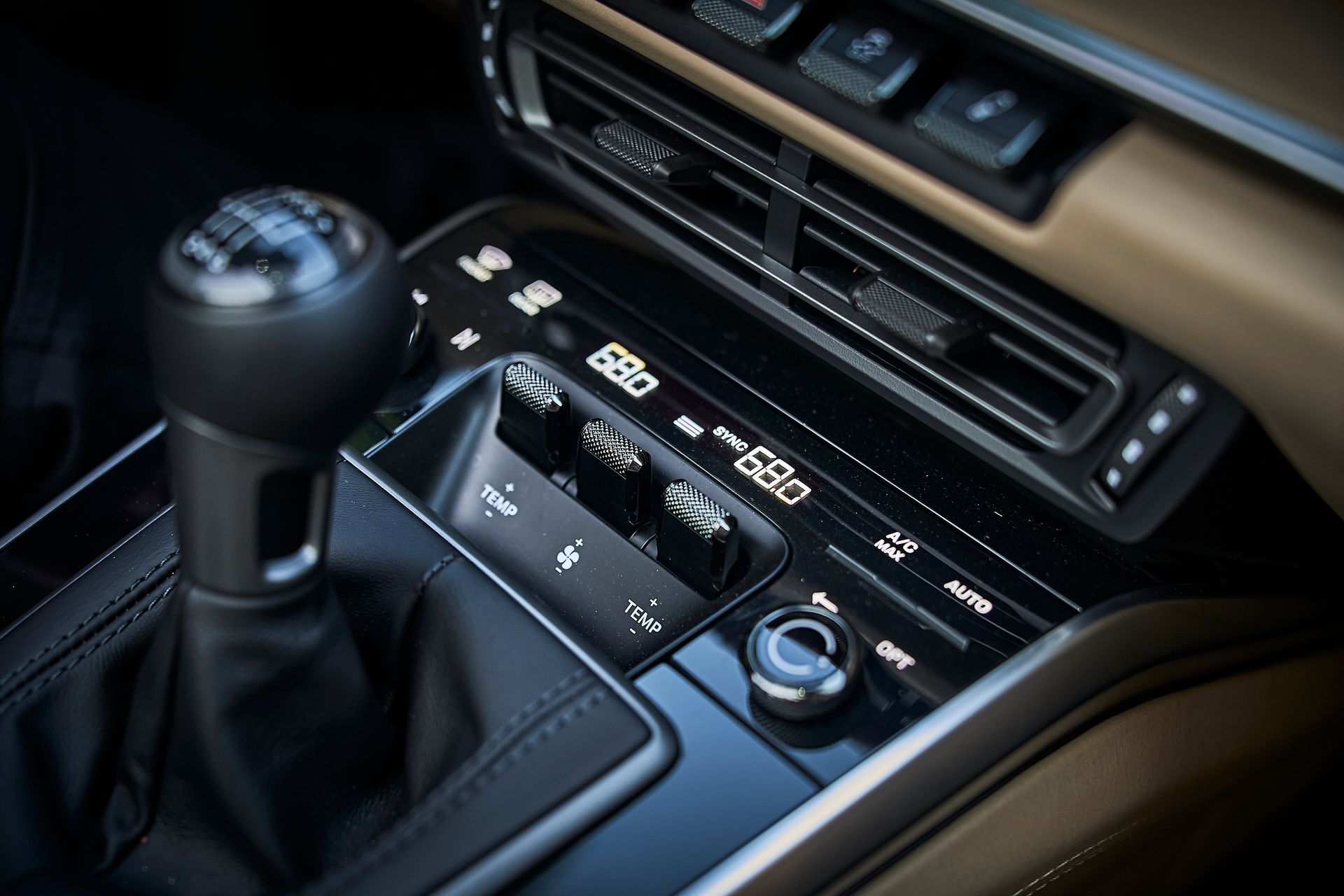 A close up of a car 's dashboard with a shifter and a climate control.