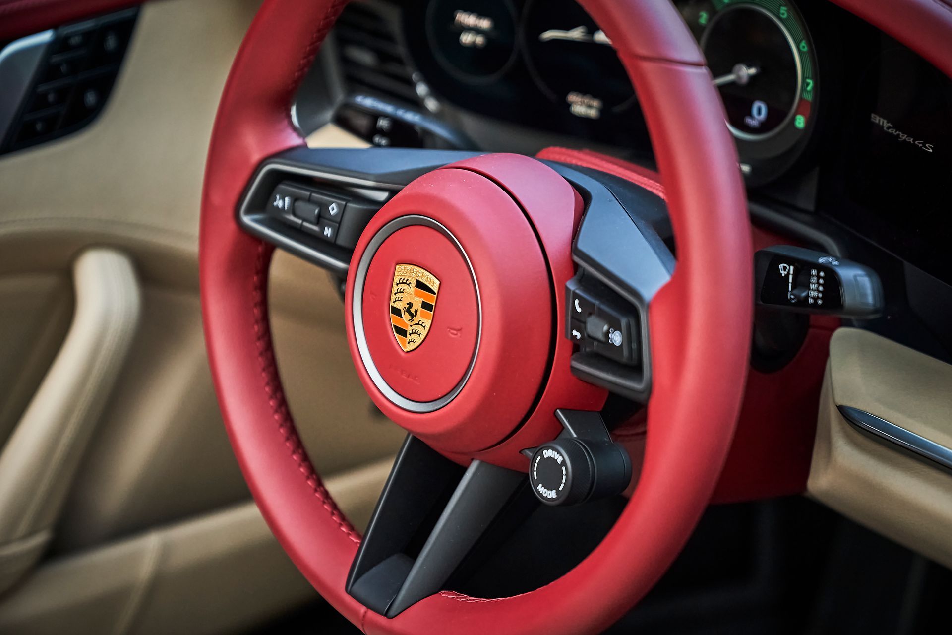 A close up of a red porsche steering wheel