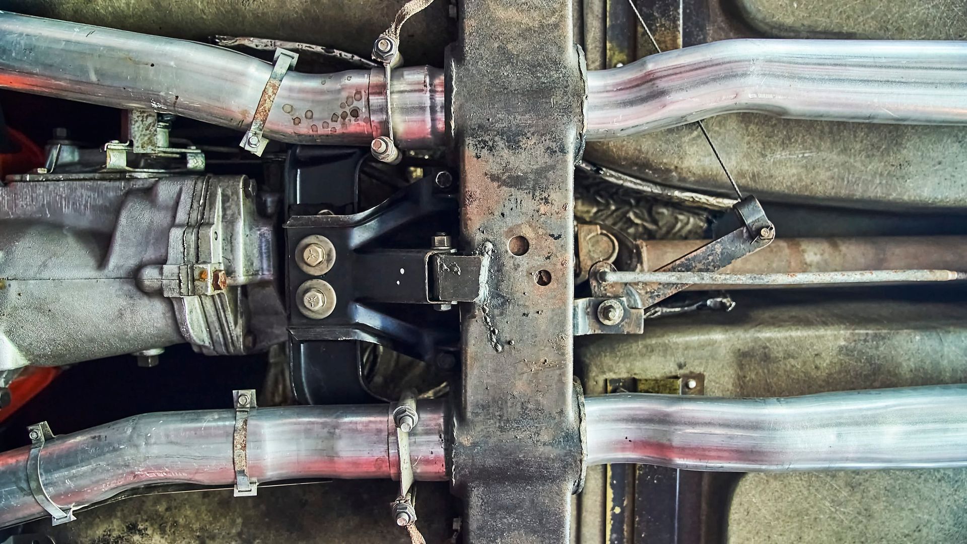 Undercarriage of a vehicle showing the transmission, drive shaft, exhaust pipes, and crossmember.