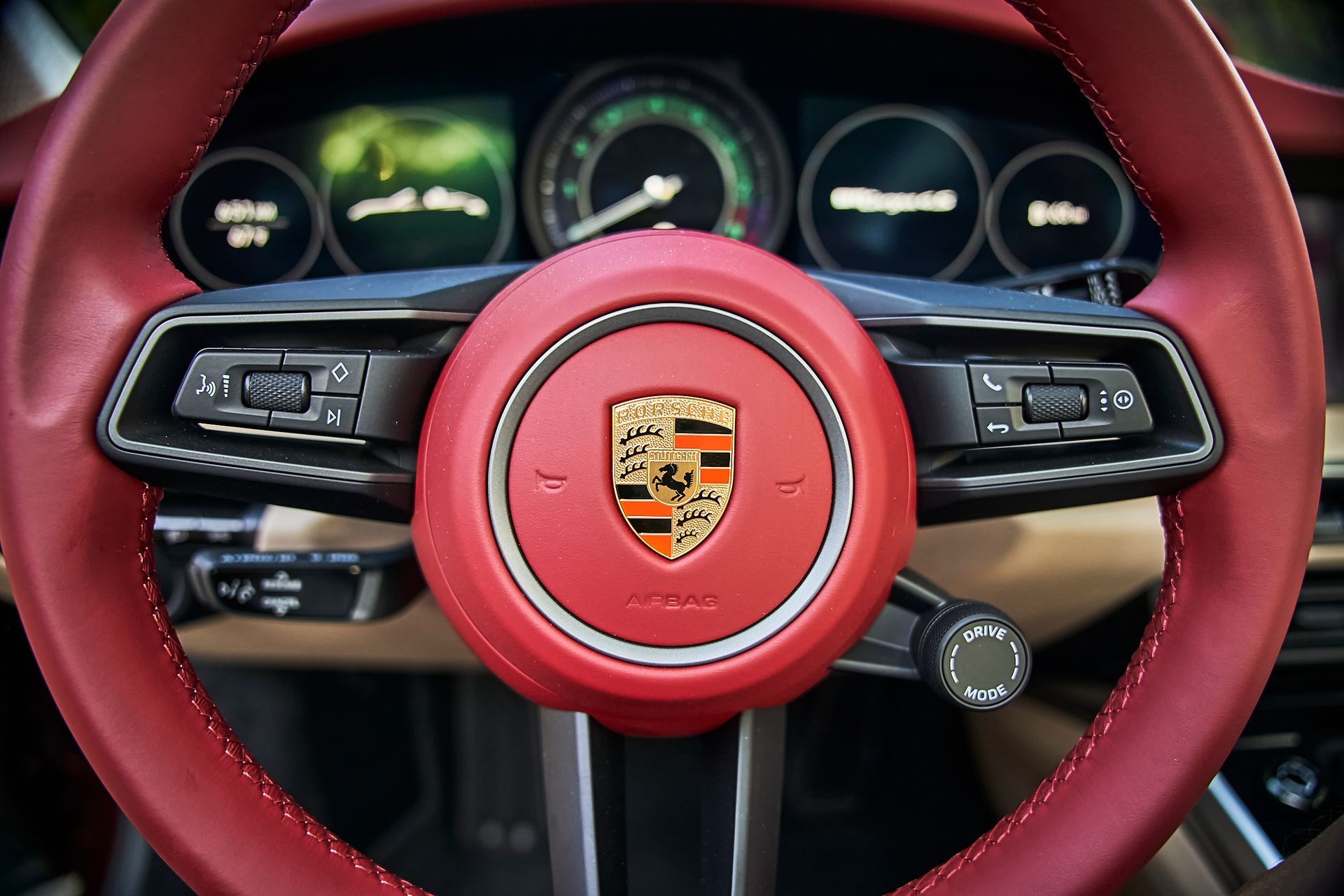 A close up of a red porsche steering wheel