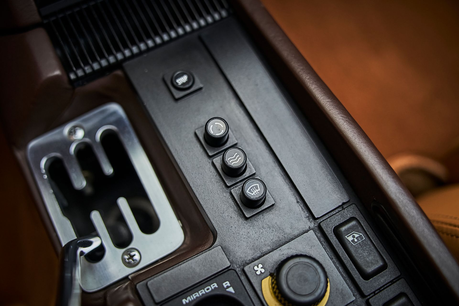 A close up of a car dashboard with a shifter and buttons.