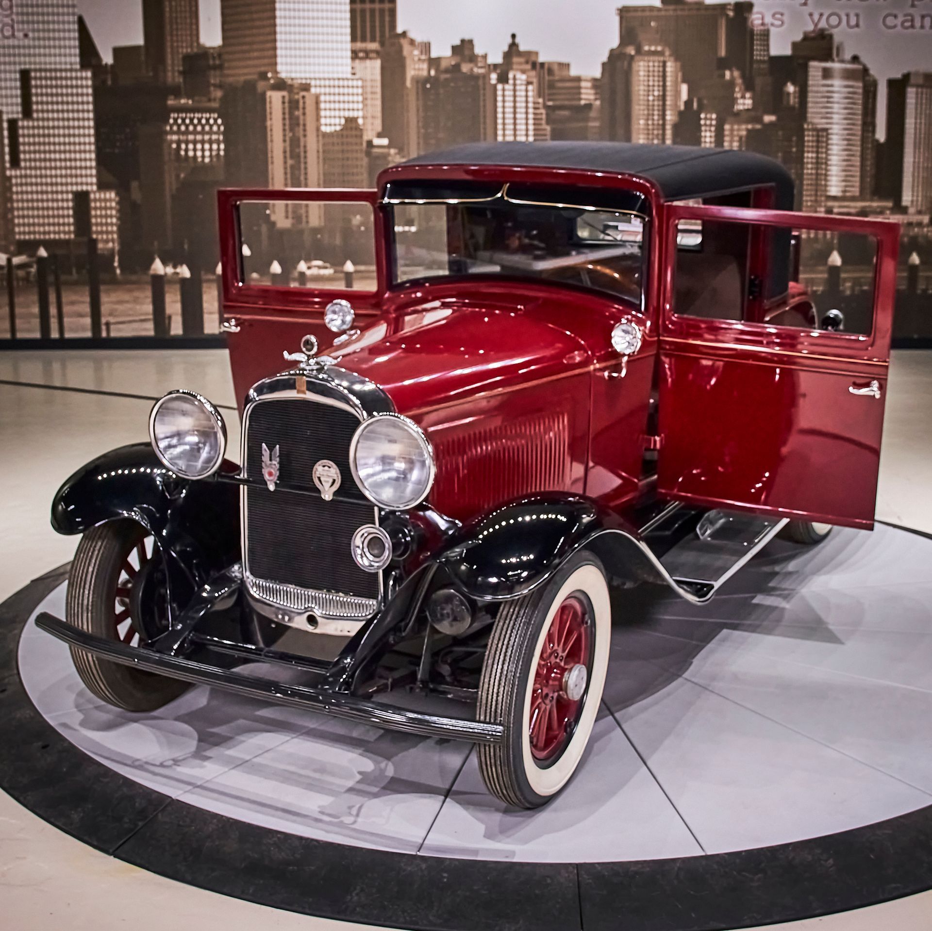 An old red car is on display with its doors open