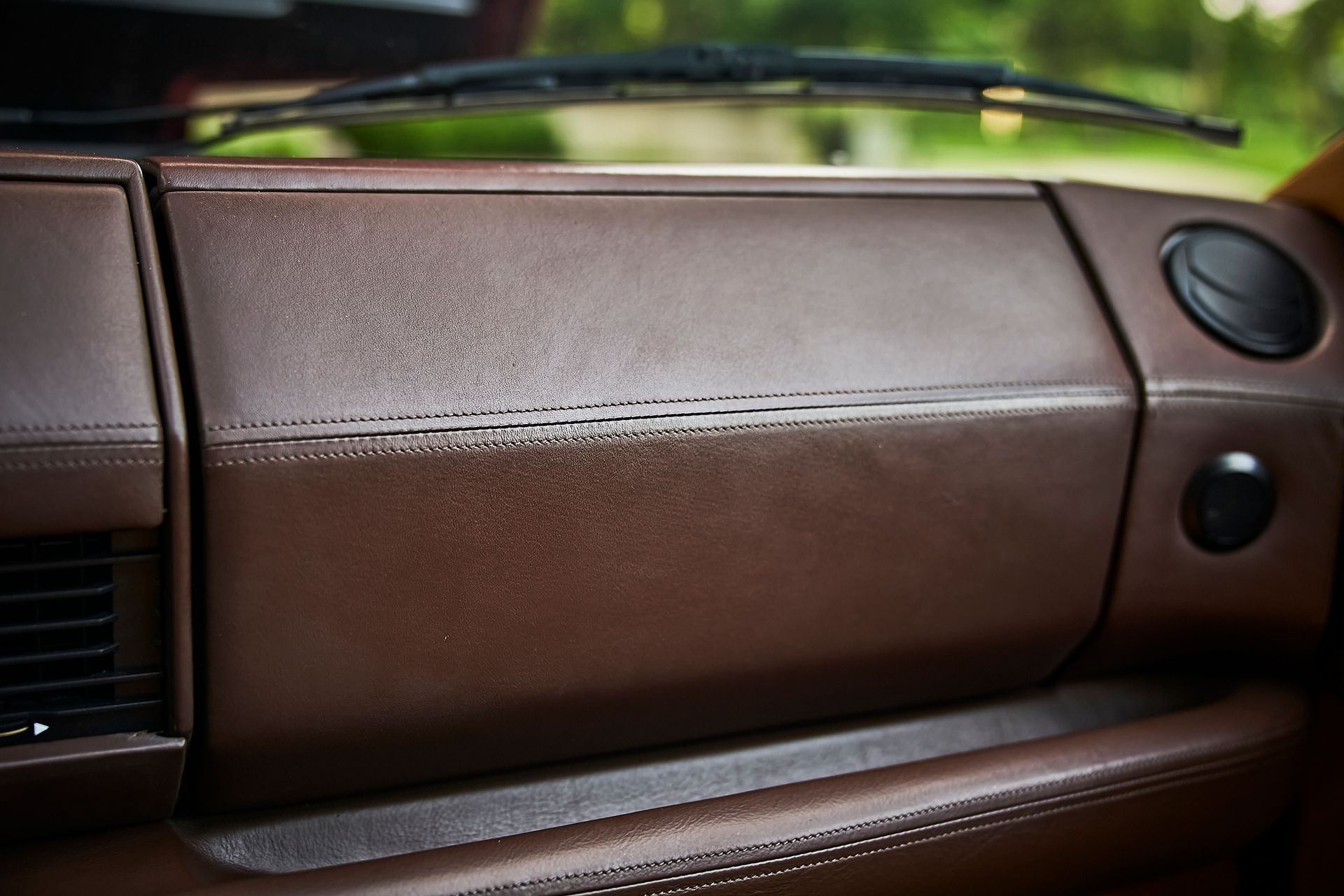 A close up of a brown leather dashboard in a car.