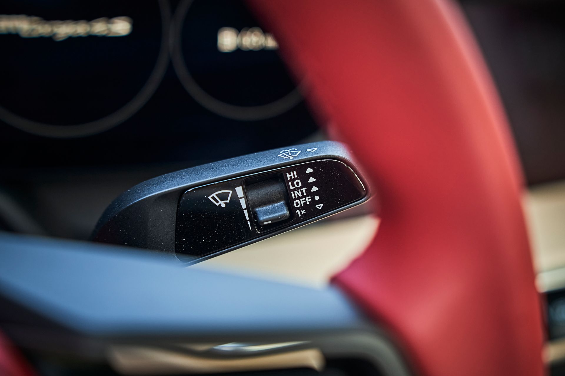 A close up of a steering wheel and wiper control in a car.