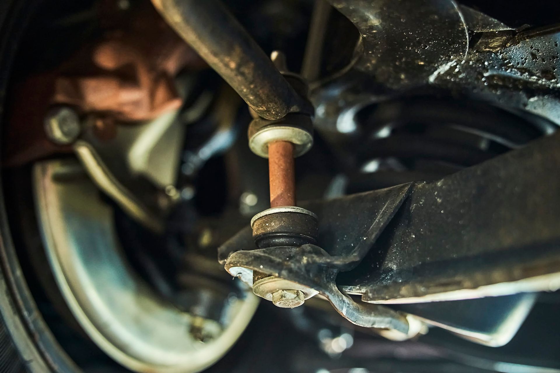 Rusty car suspension component with connecting rod and sway bar.