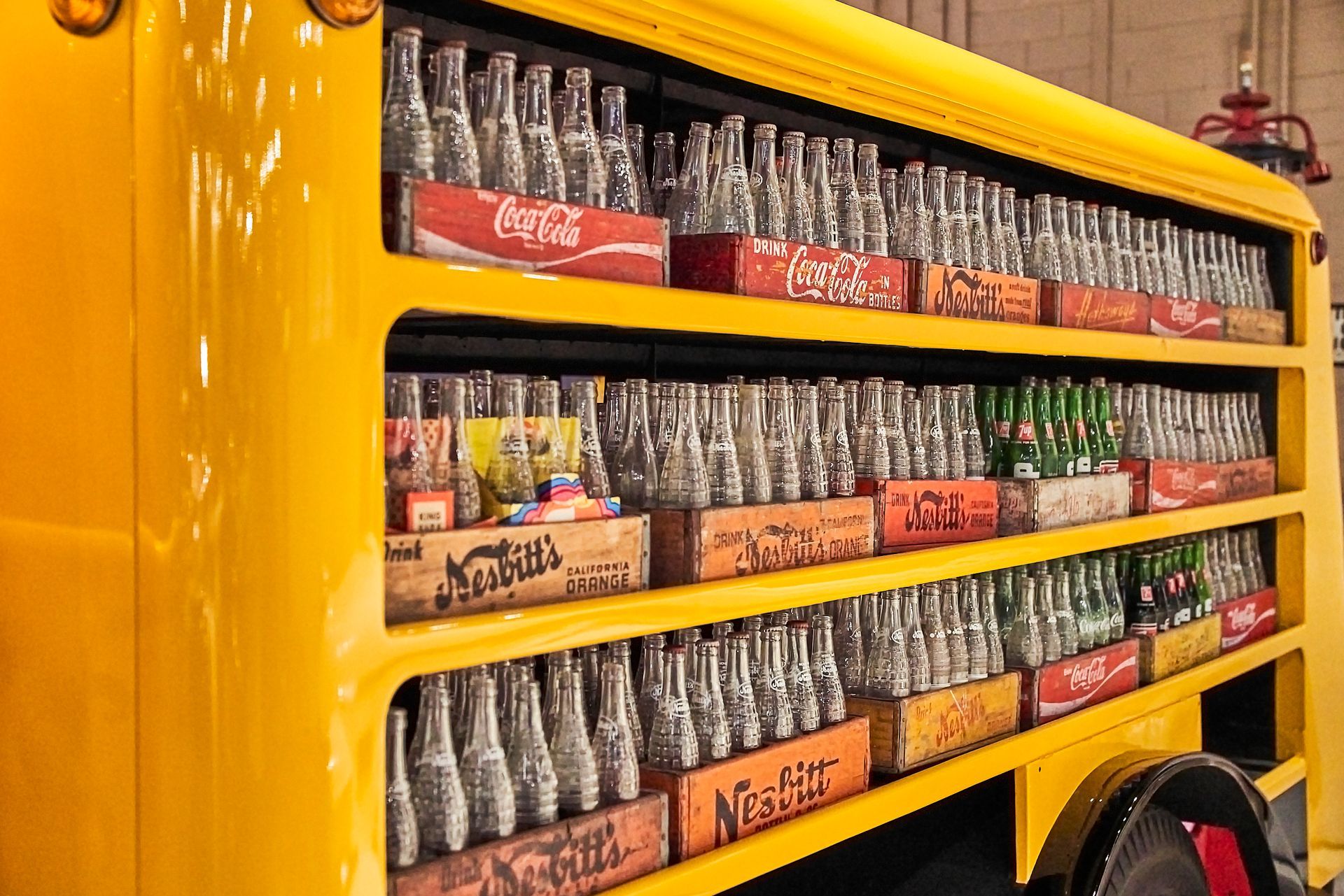 A yellow bus filled with coca cola bottles and cans.