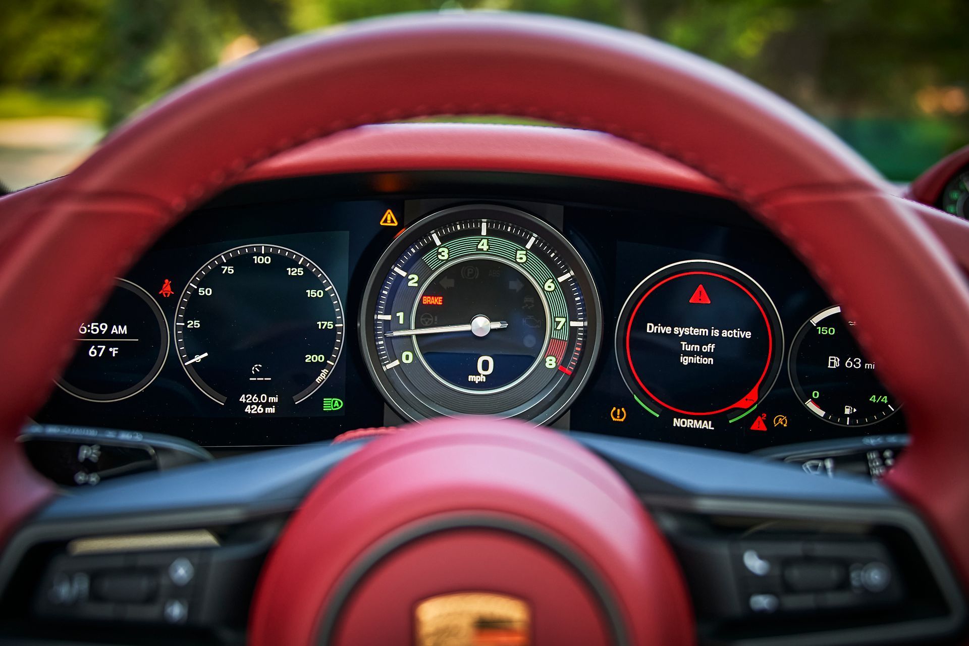 A close up of a car dashboard with a red steering wheel