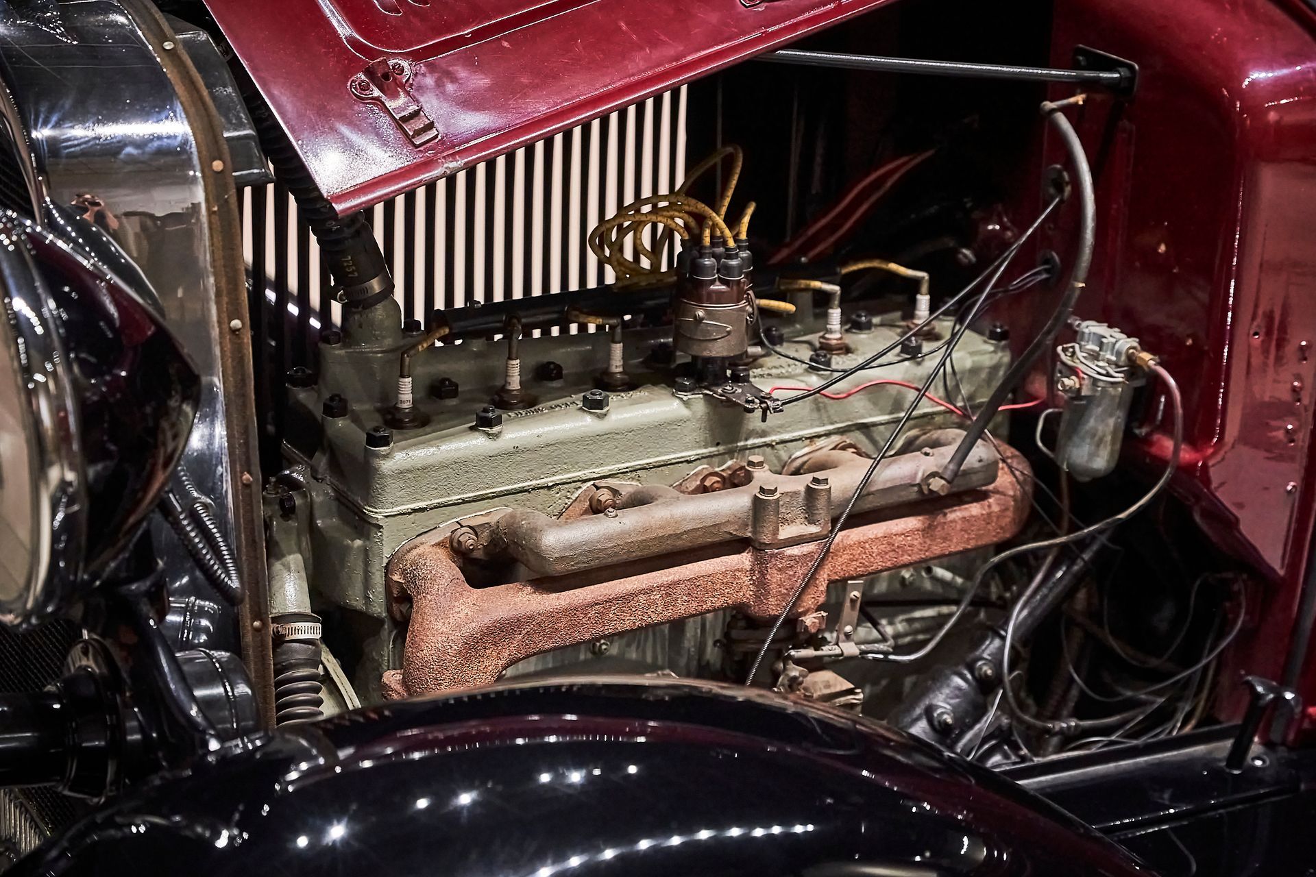 A close up of an old car engine with the hood open
