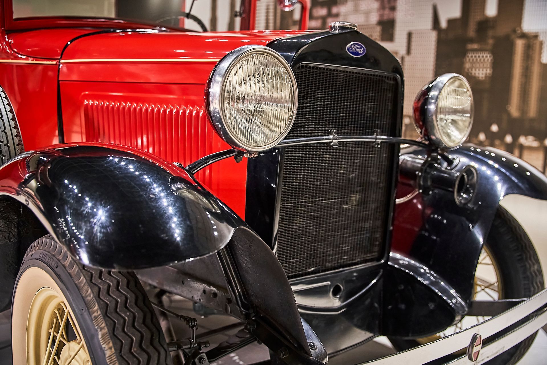 A red and black old car is parked next to a black car.