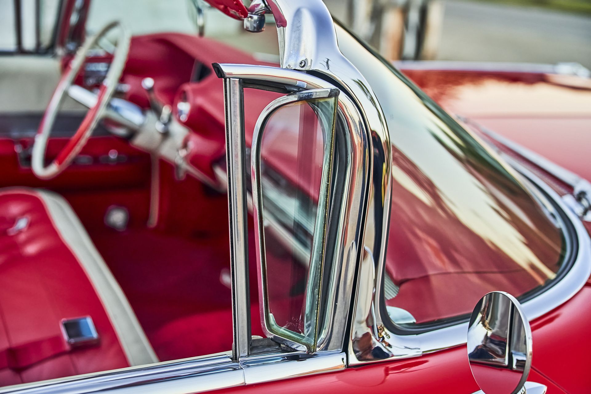 A close up of the inside of a red car with a chrome trim.