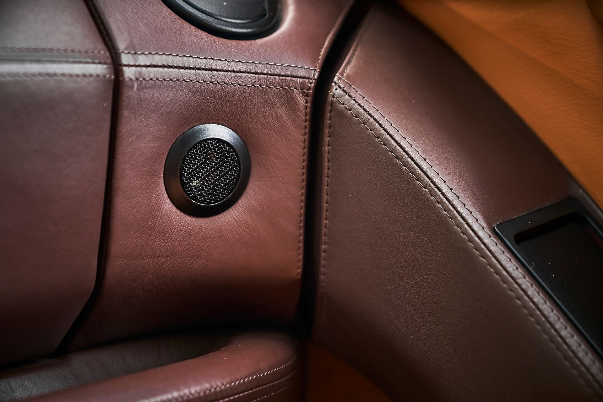 A close up of a brown leather car seat with speakers
