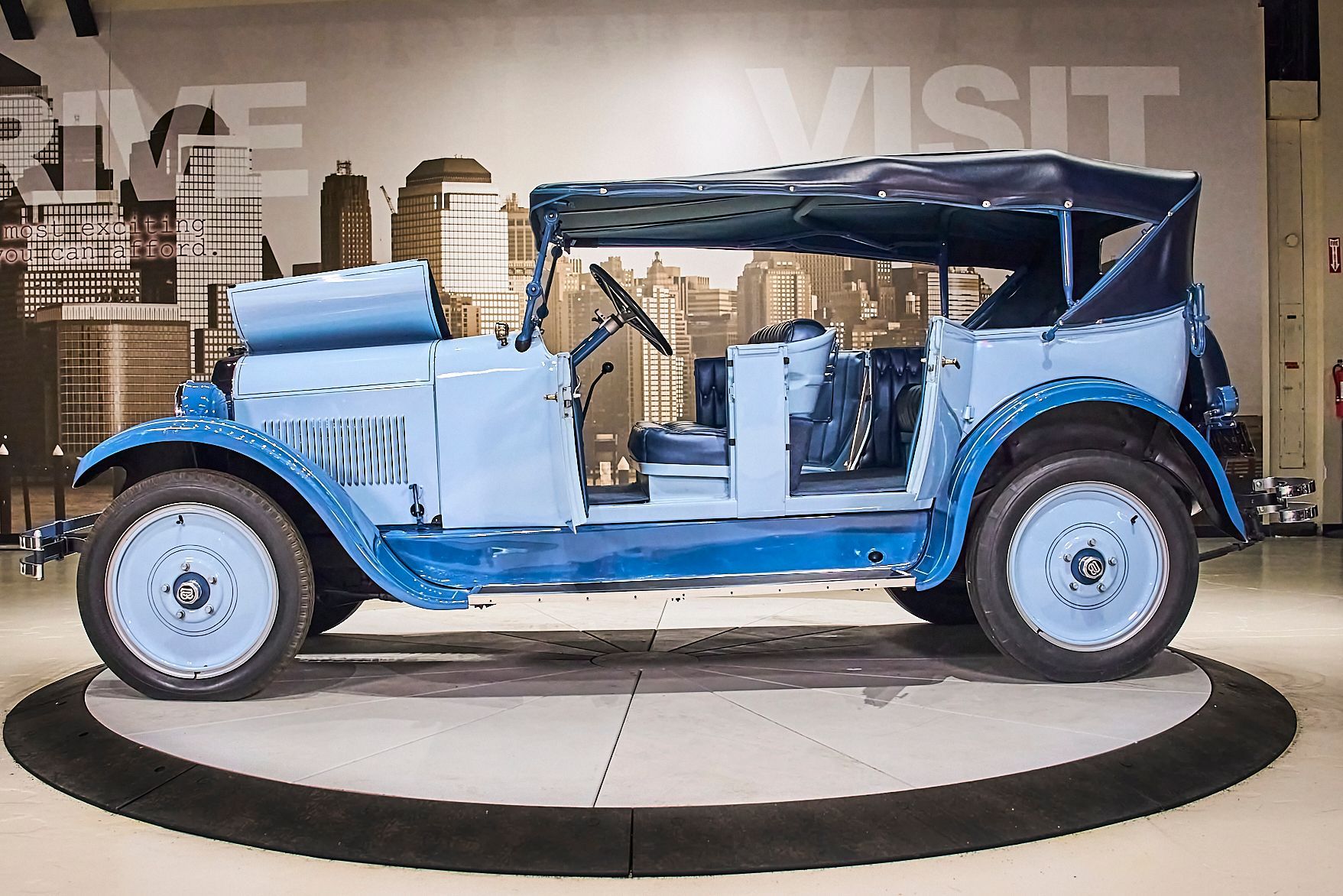 An old blue car is on display in a museum.