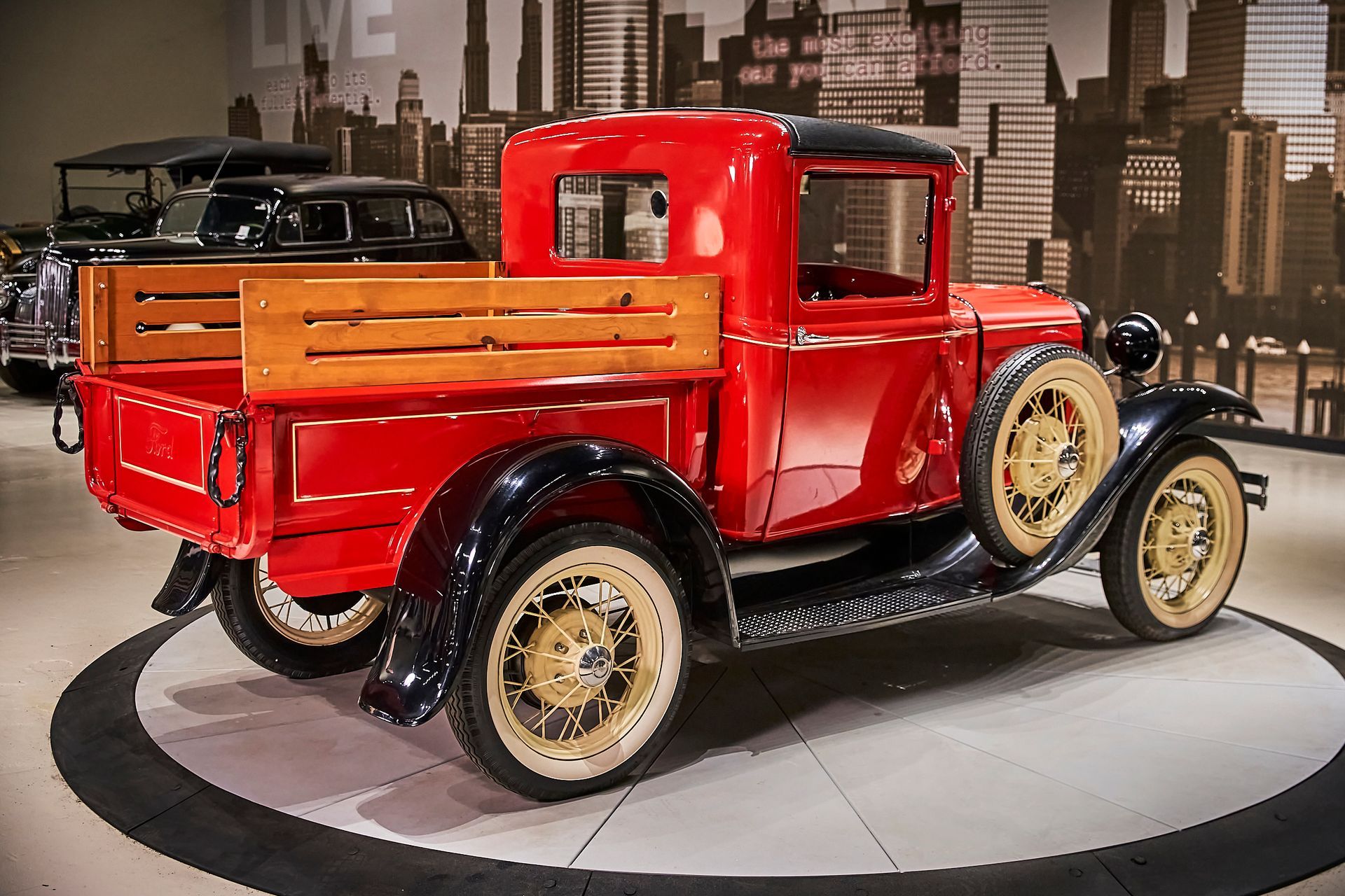 A red truck with a wooden bed is parked in a showroom.