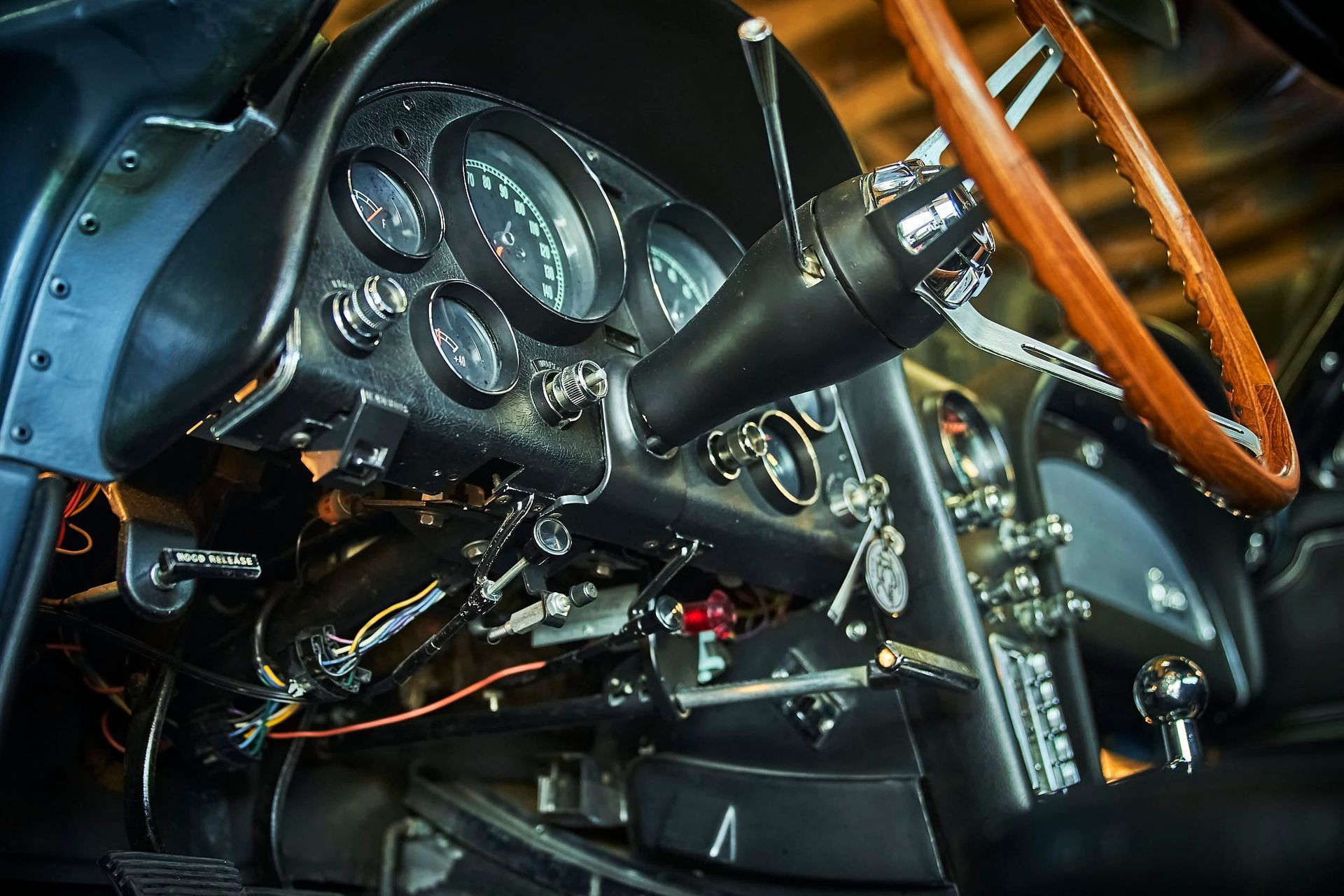 Dashboard of a classic blue Corvette, featuring gauges, a wooden steering wheel, and chrome details.