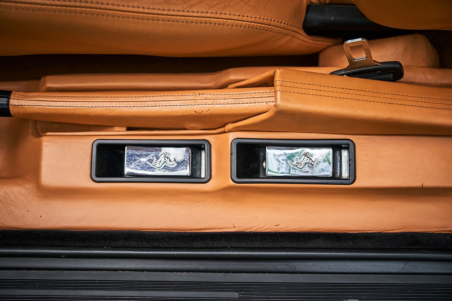 A close up of the inside of a car with a brown leather seat.