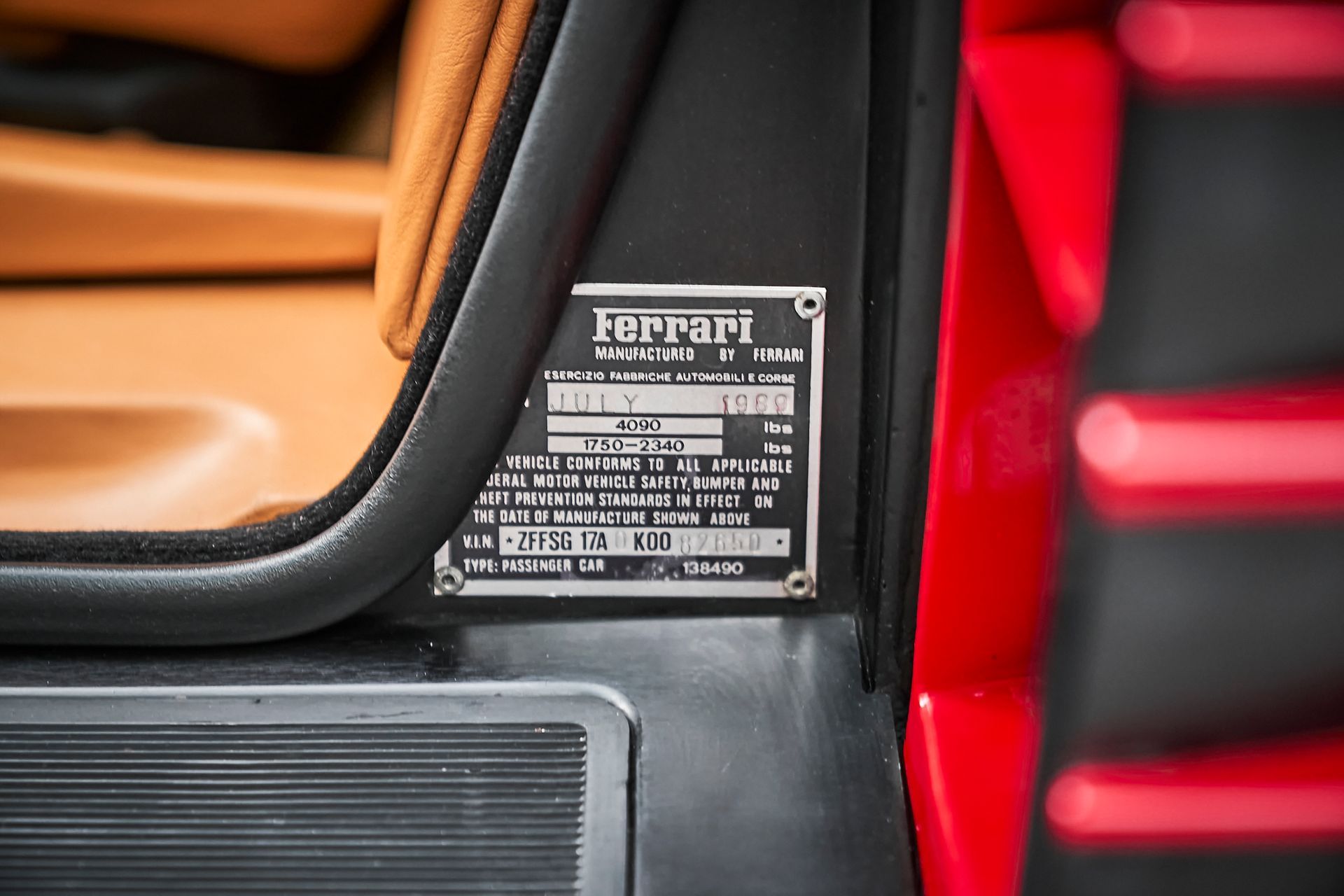 A close up of a ferrari license plate on the side of a red car.